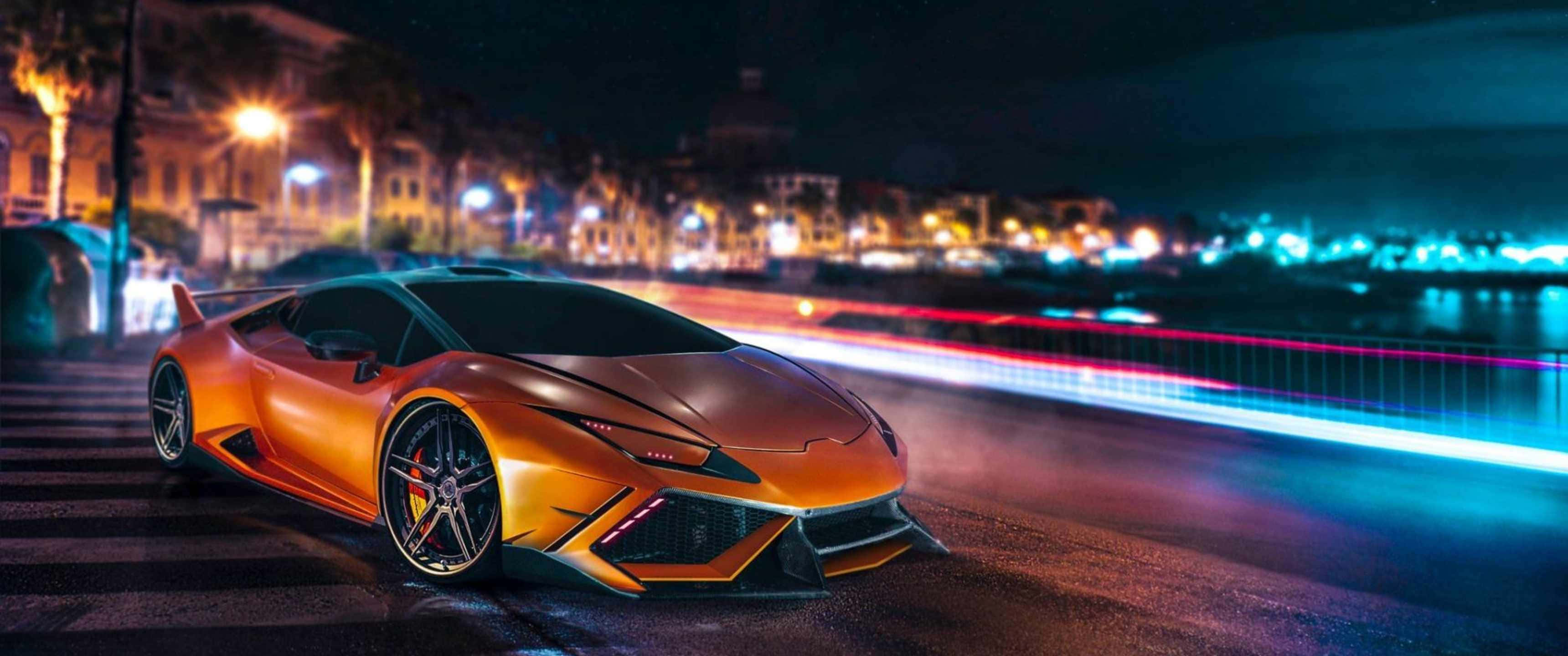 3440x1440p Lamborghini 桌布 壁紙 — 一輛發光的橙色跑車停泊在夜晚潮濕的城市街道上，伴隨著過往車輛的光跡。