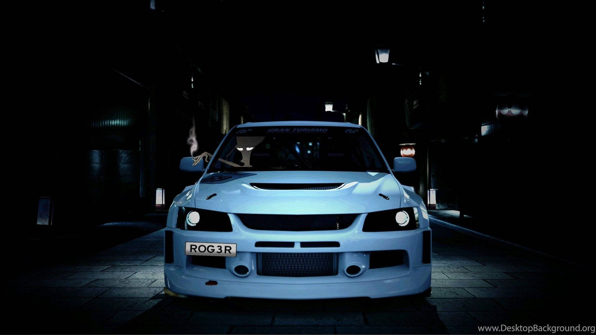 JDM 桌布 壁紙 — 一輛發光的淺藍色跑車，車牌為'ROG3R'，在黑暗的城市小巷中向前凝視，遠處的路燈照亮了小巷。