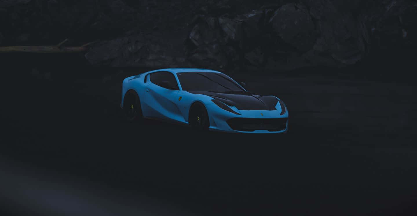 Ferrari 812 Superfast 桌布 壁紙 — 一輛發光的藍色跑車帶有黑色飾件，停在昏暗燈光下的黑暗岩石地形上。