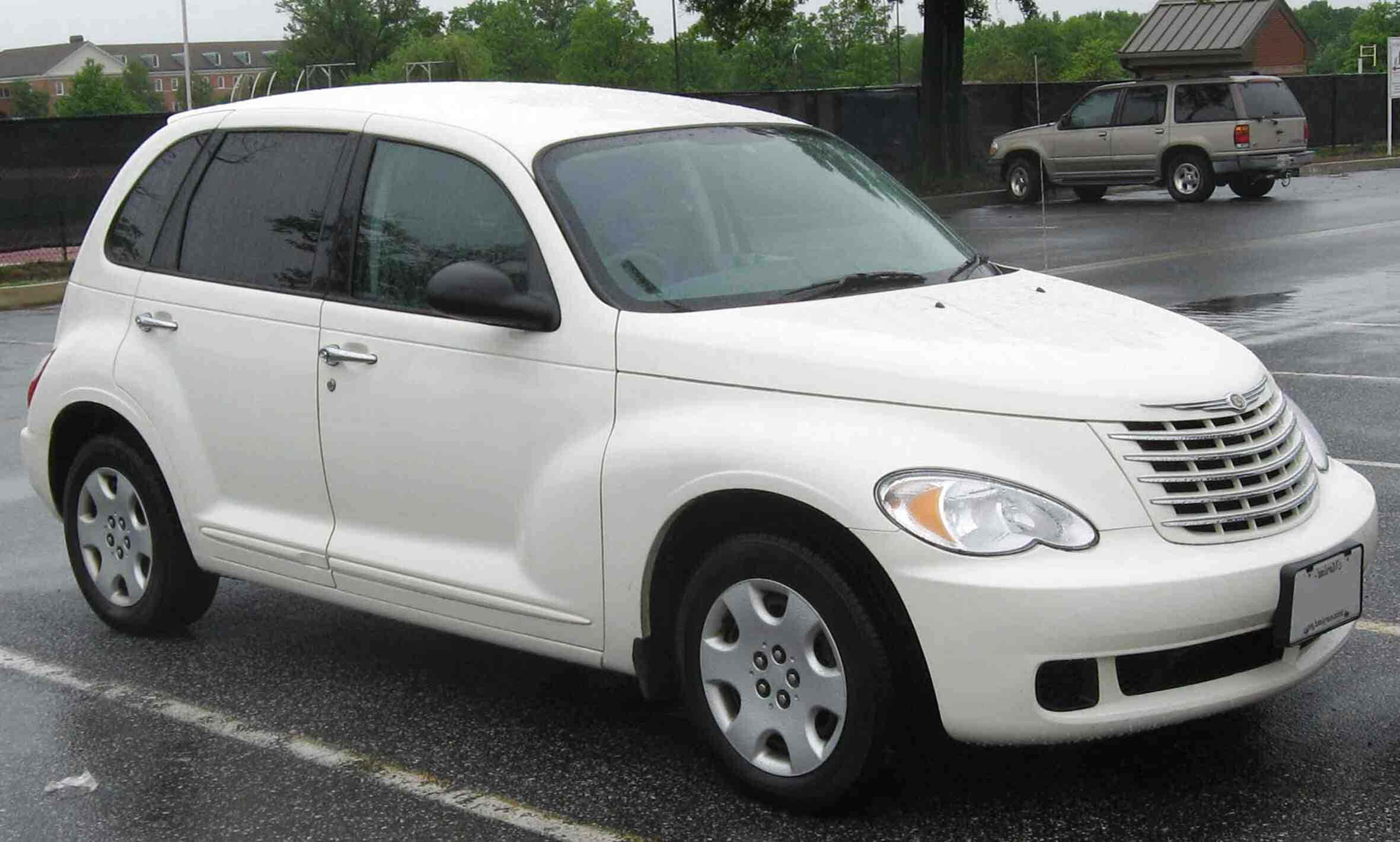 Chrysler Pt Cruiser 桌布 壁紙 — 一輛白色 Chrysler PT Cruiser 停放在潮濕的瀝青停車場，背景有樹木和圍欄。