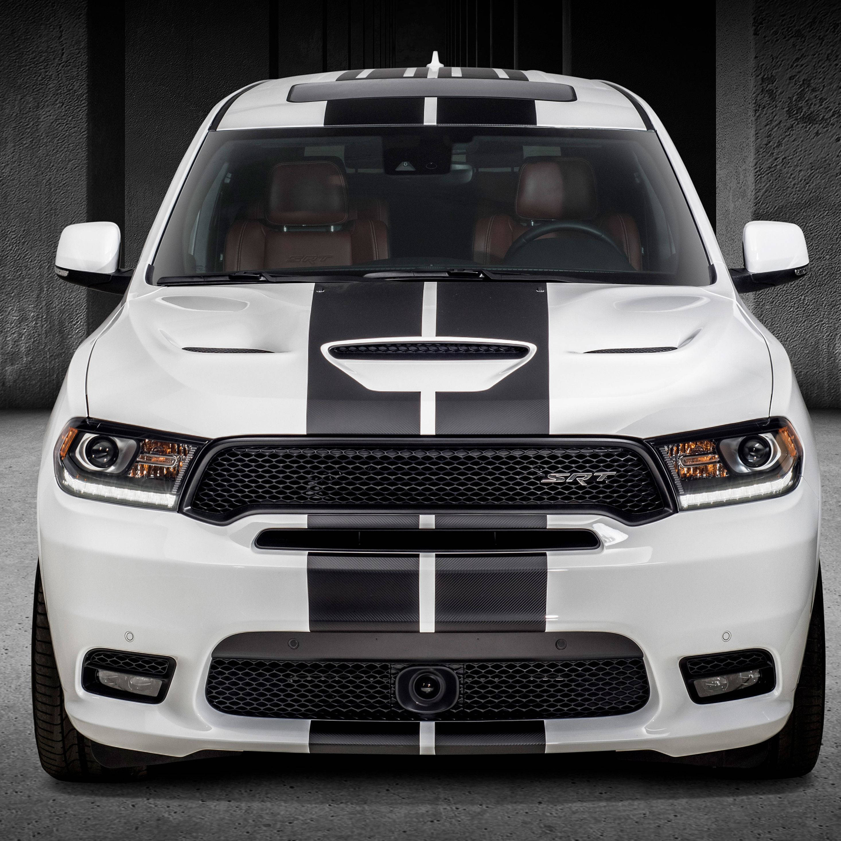 Dodge 桌布 壁紙 — 一輛白色 Dodge Durango SRT 帶有醒目的黑色賽車條紋，在昏暗的工業車庫中向前凝視。