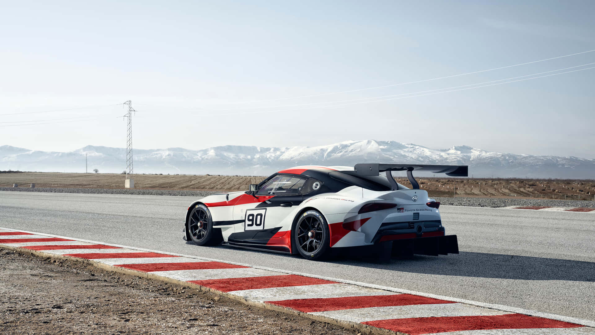 白色、紅色和黑色賽車在賽道上，背景是白雪覆蓋的山脈。 — Toyota Supra Mk4 壁紙