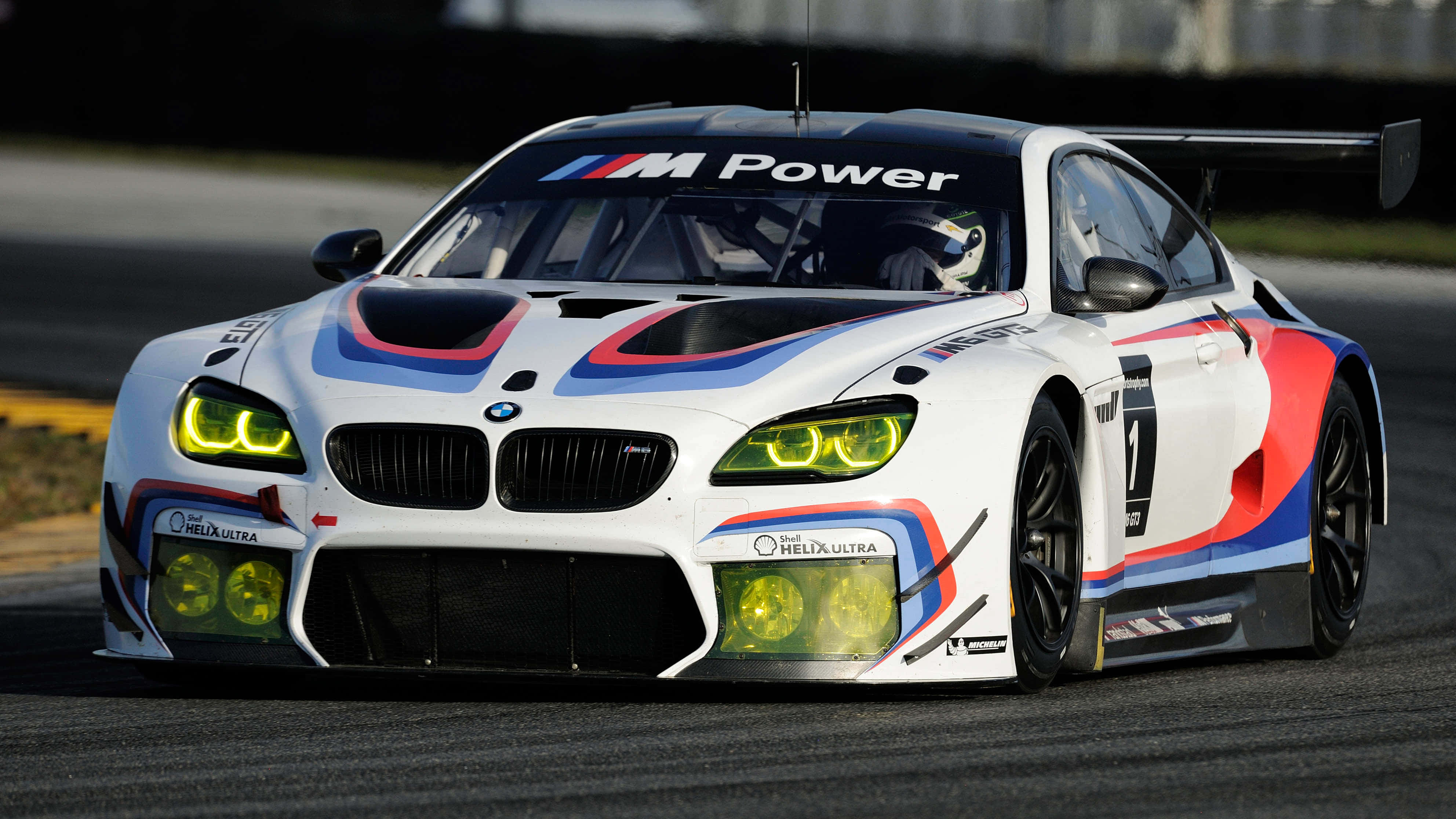 Bmw M6 桌布 壁紙 — 一輛白色BMW M Power賽車在明亮的日光下，在賽道上以黃色發光頭燈飛馳。