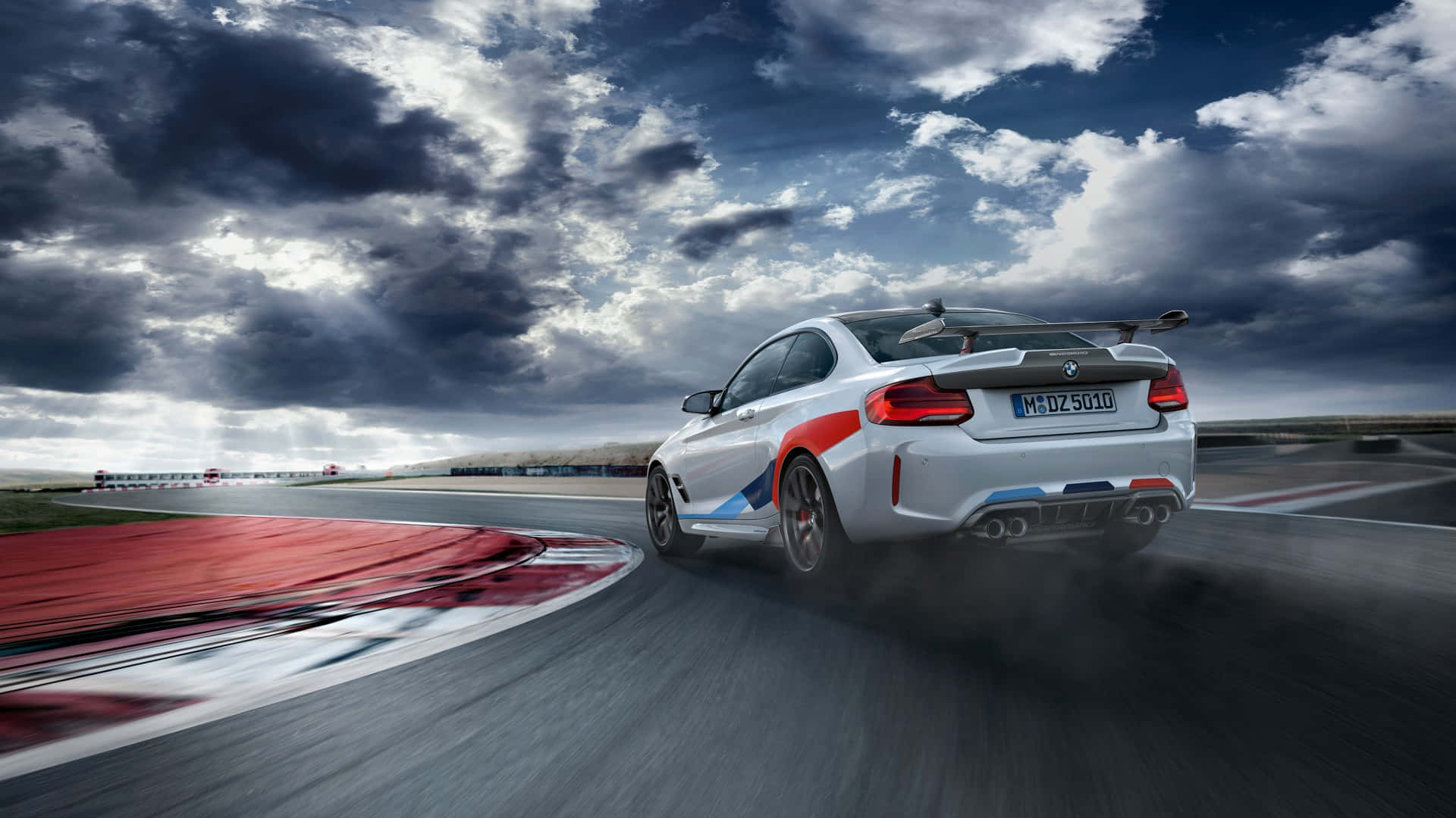 Bmw M Series 桌布 壁紙 — 一輛白色BMW M2賽車在戲劇性的多雲天空下於賽道彎角漂移。