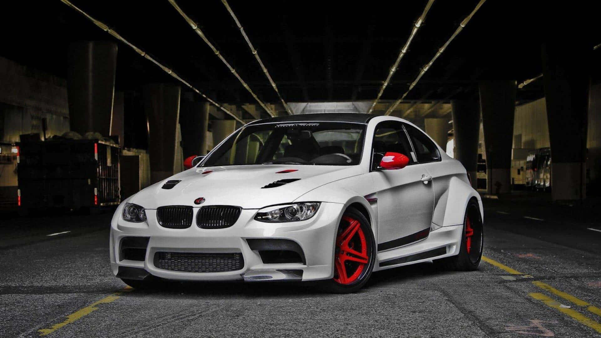 跑車 桌布 壁紙 — 一輛白色BMW M3，帶有紅色點綴和定制輪圈，夜間停放在燈光昏暗的混凝土天橋下。