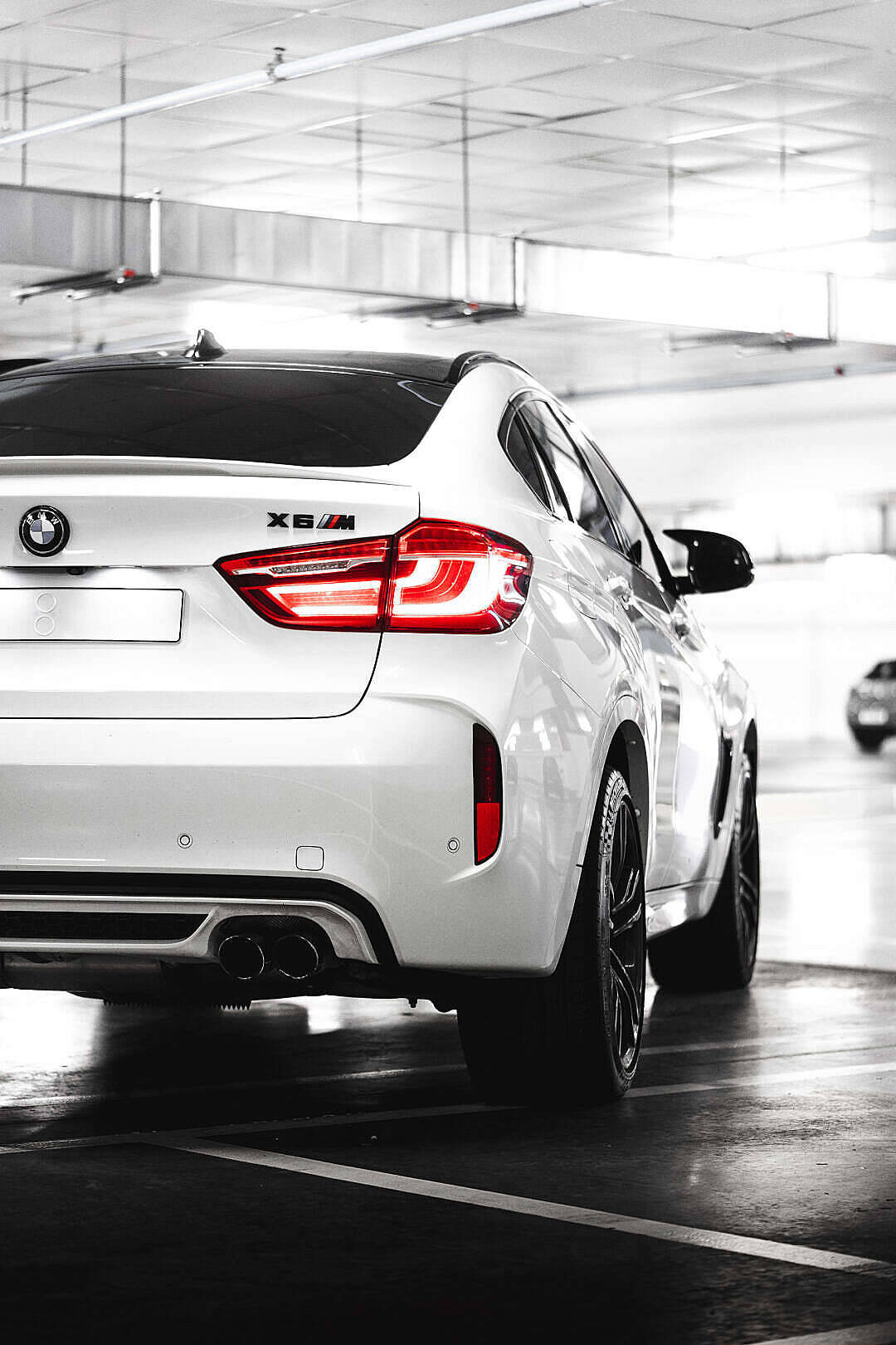 m 桌布 壁紙 — 一輛白色BMW X6M SUV，紅色尾燈亮著，停放在高天花板的簡陋地下停車場。