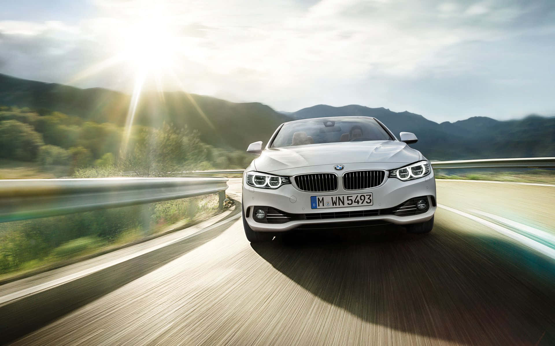 Bmw 4 Series 桌布 壁紙 — 一輛白色BMW敞篷車在蜿蜒的山路上疾馳，伴隨著陽光爆發的照明和模糊的動態效果。