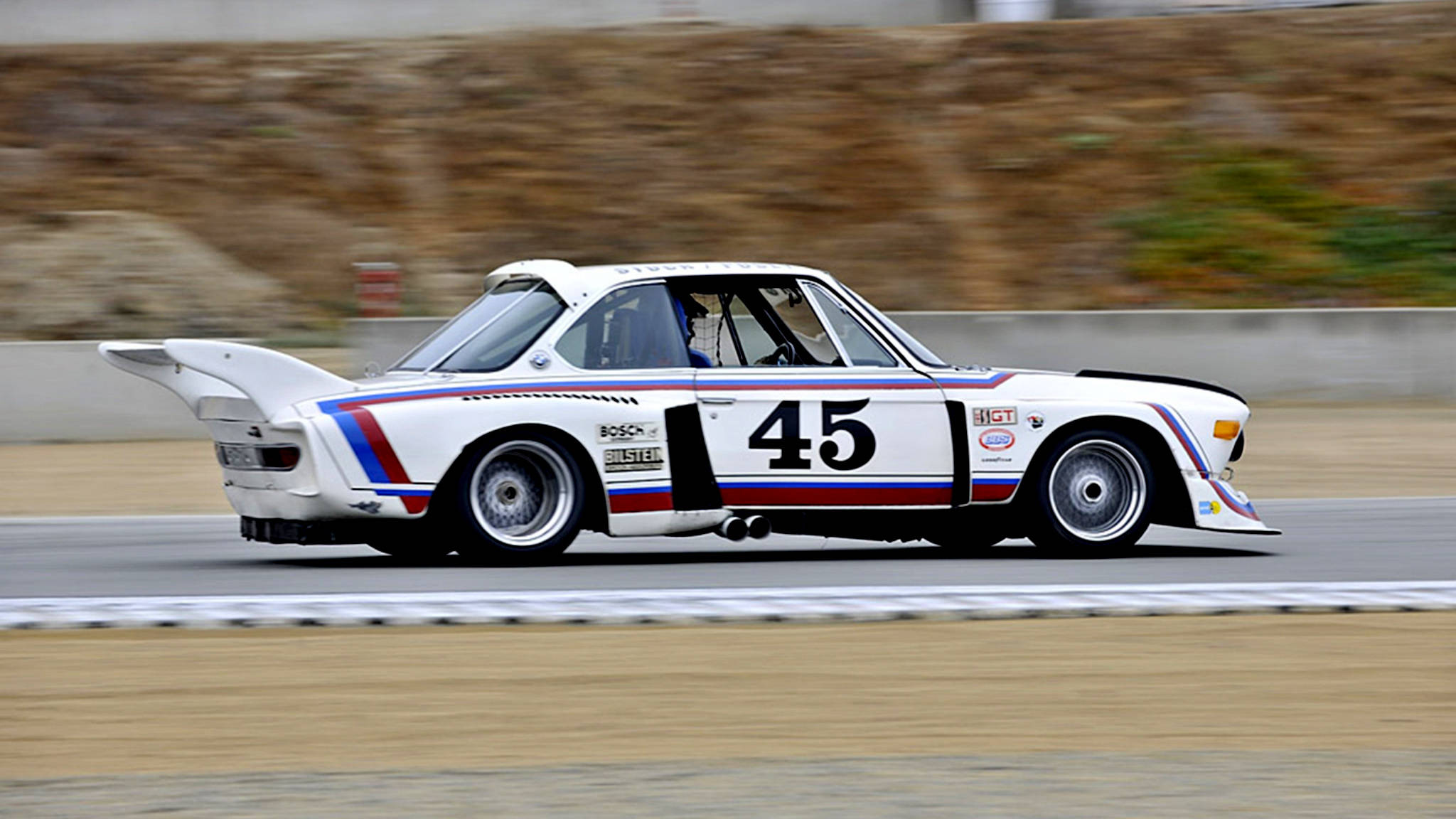 classic bmw 桌布 壁紙 — 一輛白色BMW賽車，編號45，在賽道上疾馳，背景模糊。