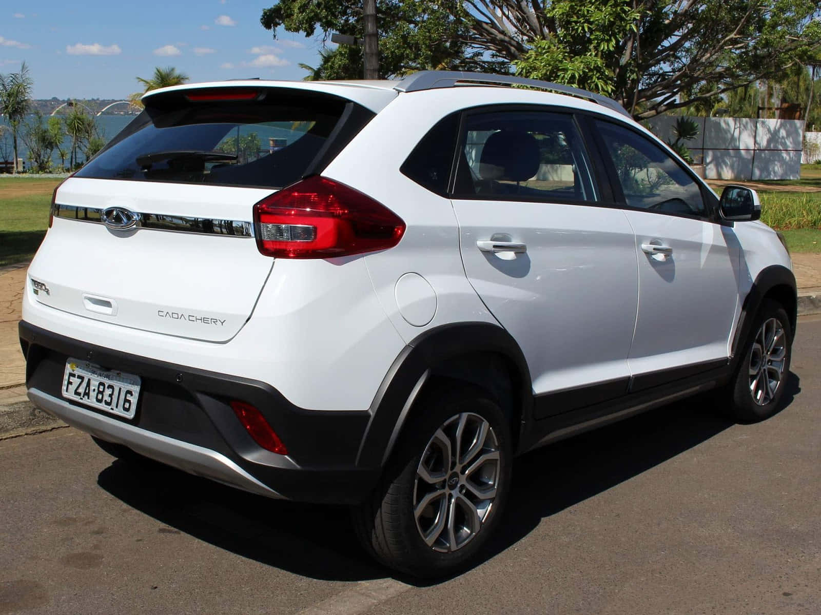 Chery 桌布 壁紙 — 一輛白色Chery Tiggo 3x SUV停放在陽光明媚的街道上，背景有樹木和水面。