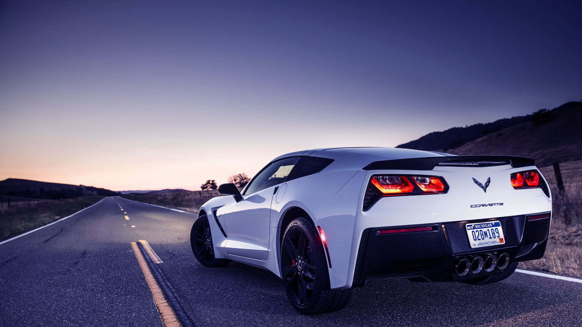 corvette 桌布 壁紙 — 一輛白色Corvette跑車，紅色尾燈發光，在暮色中行駛在沙漠公路上。
