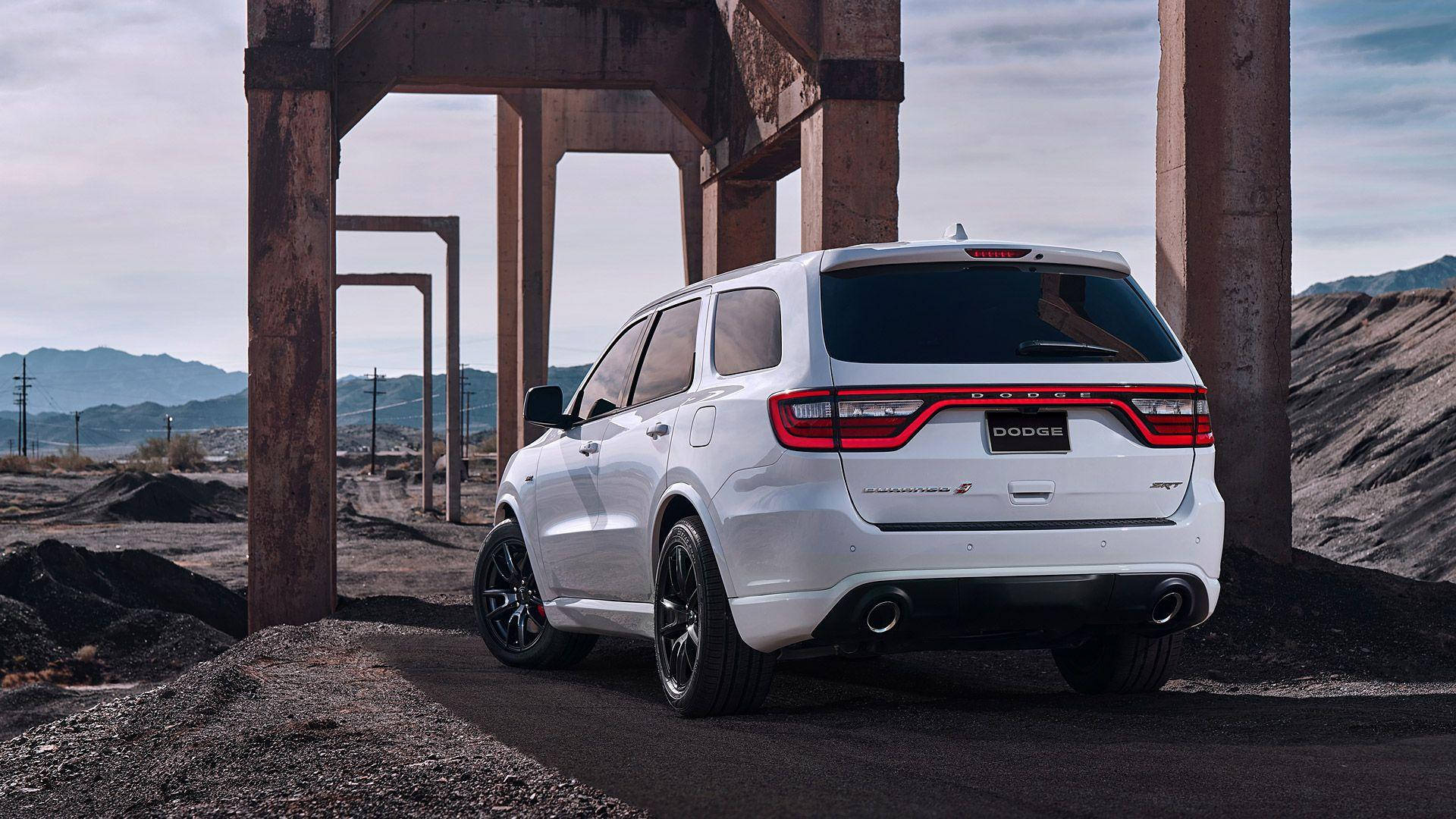 Dodge 桌布 壁紙 — 一輛白色Dodge Durango SUV，紅色尾燈，停泊在生鏽的工業鋼樑下，背景是荒蕪的採石場景觀。