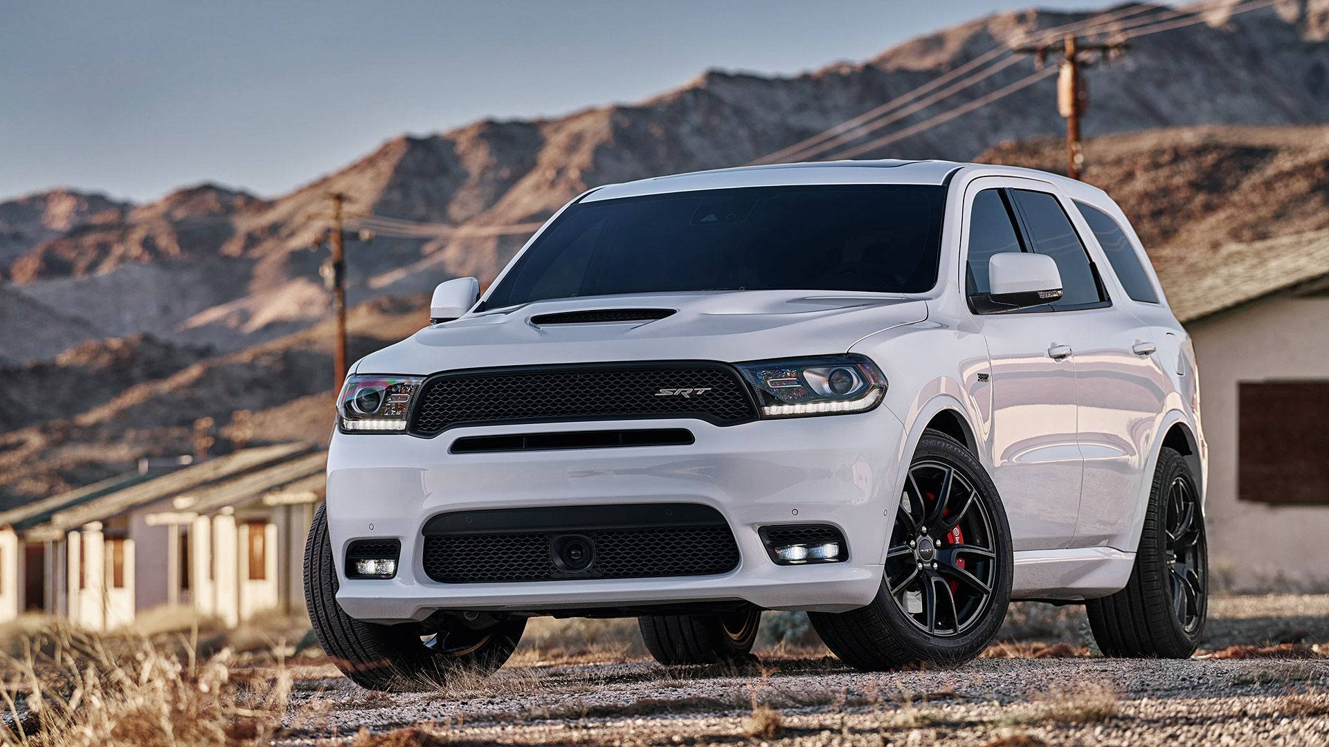 Dodge 桌布 壁紙 — 一輛白色Dodge Durango SRT SUV搭配黑色輪圈，在沙漠景觀中傲然矗立，背後有山脈和古老建築。