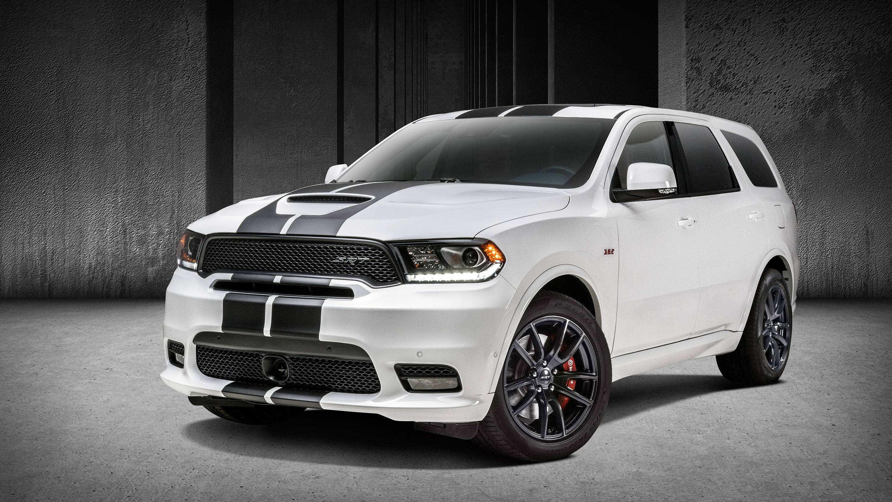 Dodge 桌布 壁紙 — 一輛白色Dodge Durango SRT，帶有黑色賽車條紋和紅色制動卡鉗，矗立在簡約的混凝土工作室中。