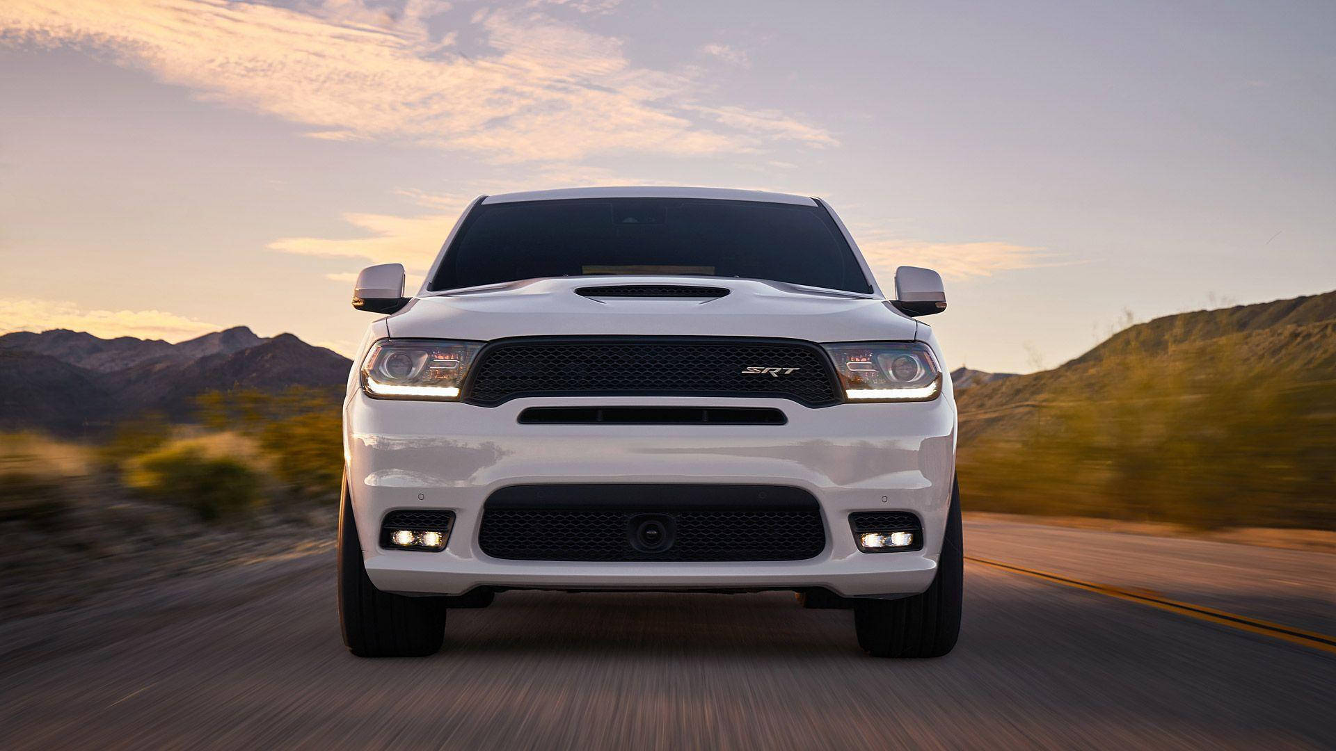 Dodge 桌布 壁紙 — 一輛白色Dodge Ram SRT卡車在日落時分的沙漠公路上向鏡頭疾馳，背景是模糊的山脈。