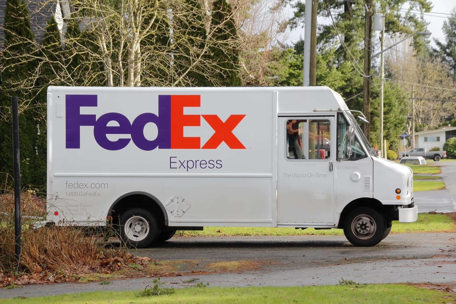 聯邦快遞 桌布 壁紙 — 一輛白色FedEx Express送貨車停在潮濕的住宅街道上，街道兩旁是光禿禿的樹木和郊區房屋。