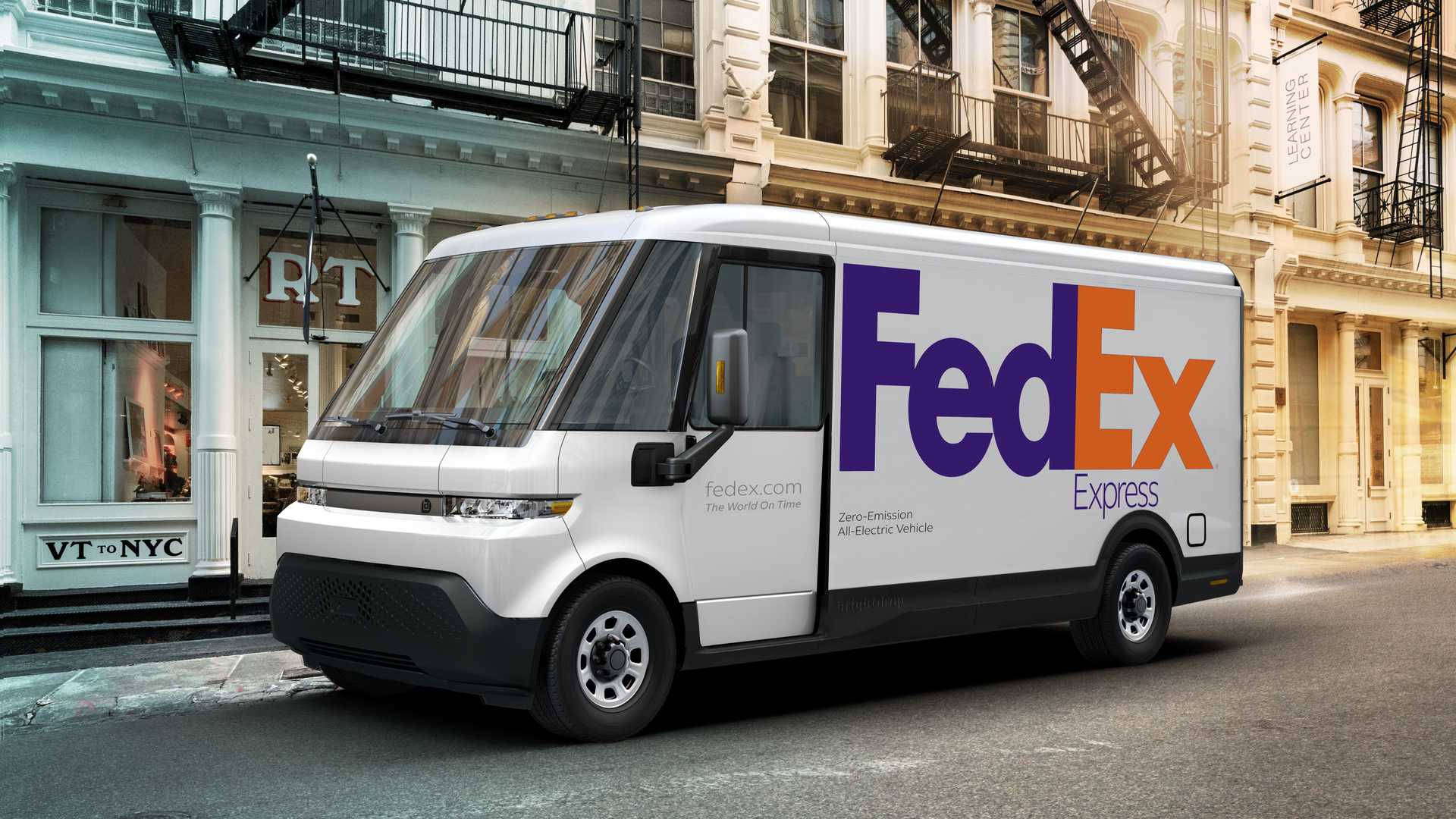 聯邦快遞 桌布 壁紙 — 一輛白色FedEx電動送貨車停放在城市的街道上，背景有歷史建築和防火梯。