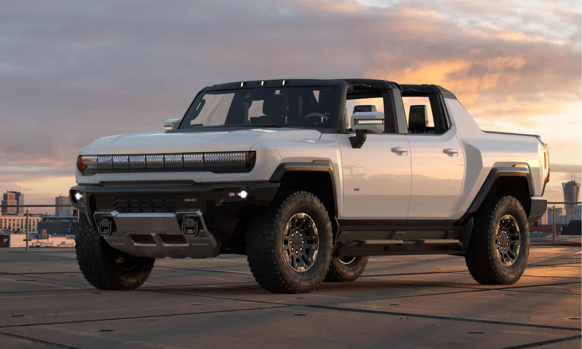 Truck 桌布 壁紙 — 一輛白色GMC Hummer EV電動皮卡車停在天台上，背景是日落時分的城市天際線。