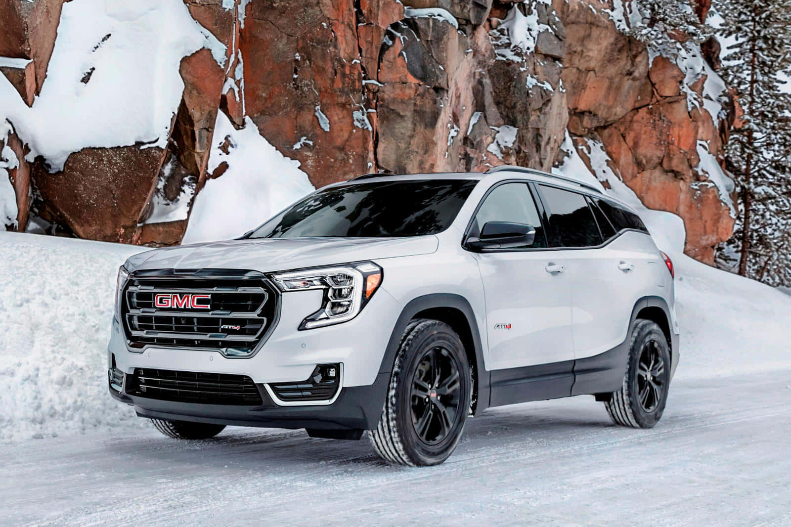 Gmc Terrain 桌布 壁紙 — 一輛白色GMC SUV配黑色輪胎，停泊在雪地上，背景是覆蓋著白雪的微紅色岩層。