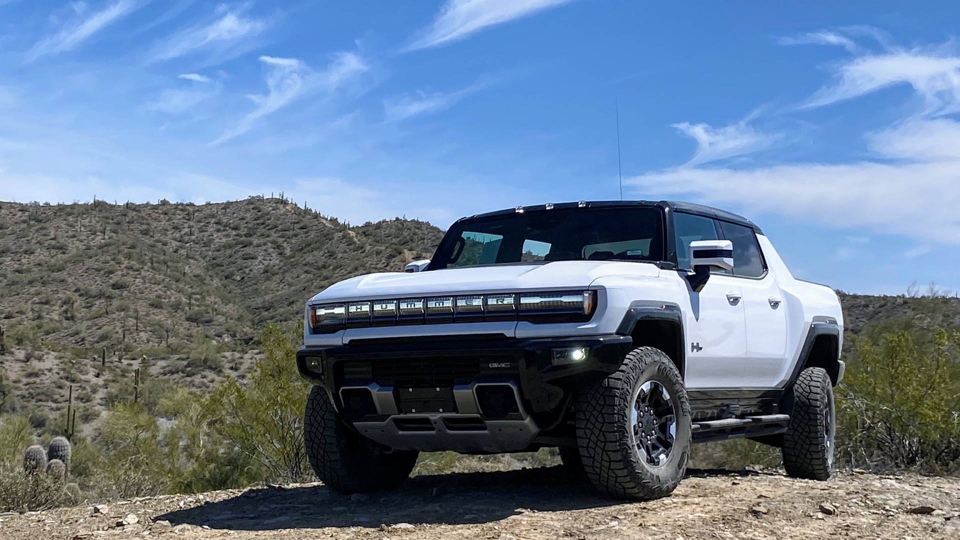 Truck 桌布 壁紙 — 一輛白色Hummer EV皮卡車在岩石沙漠小徑上大膽地停放，天空湛藍，雲朵稀疏。