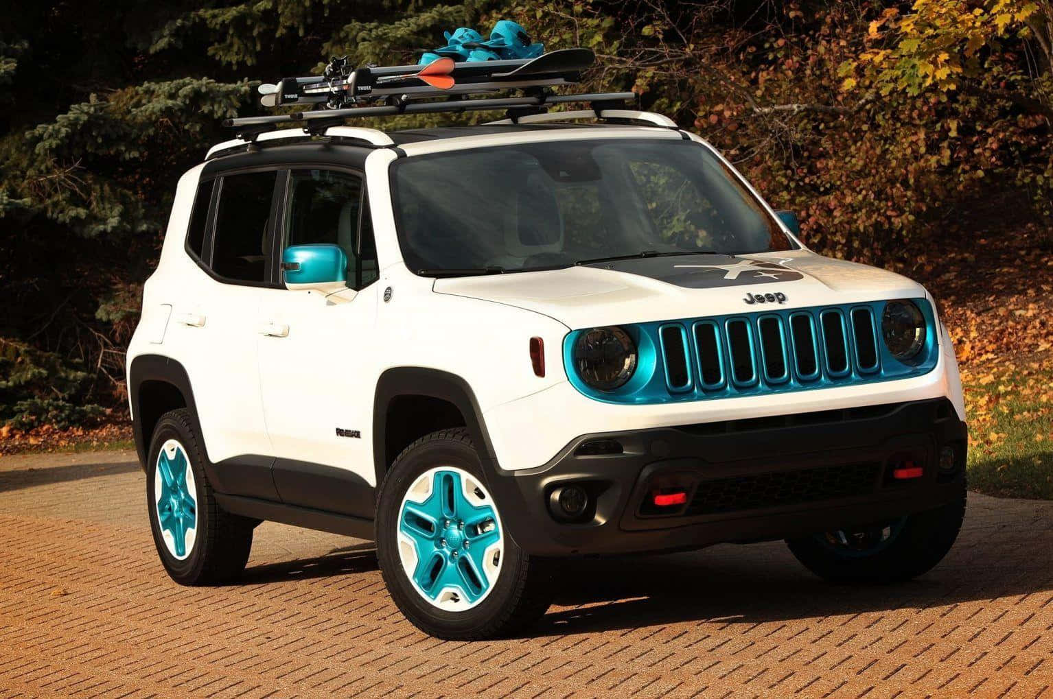 Jeep Renegade 桌布 壁紙 — 一輛白色Jeep Renegade帶有鮮豔的藍綠色點綴和車頂滑雪板，停在鋪滿秋葉的磚砌車道上。