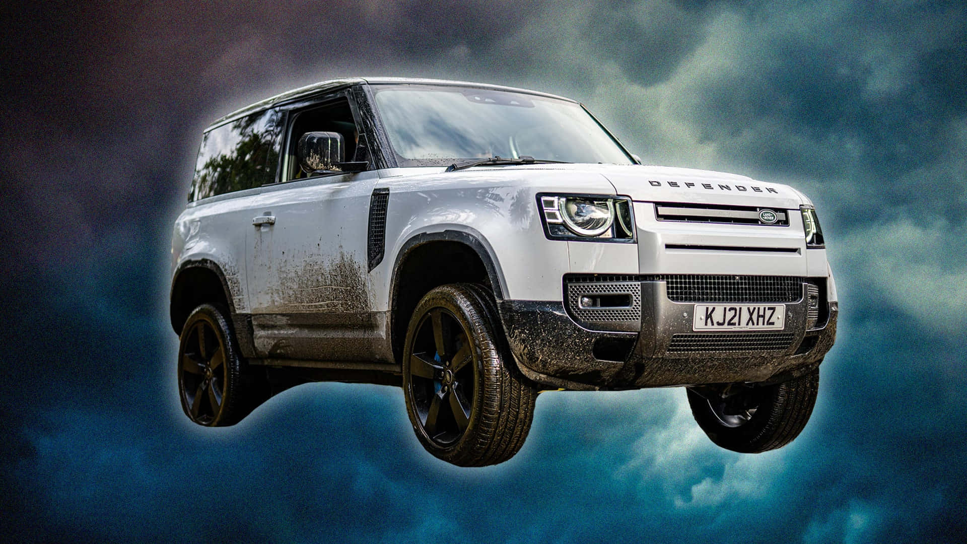 Land Rover Defender 桌布 壁紙 — 一輛白色Land Rover Defender懸浮在風暴雲層中輪胎沾滿泥漿