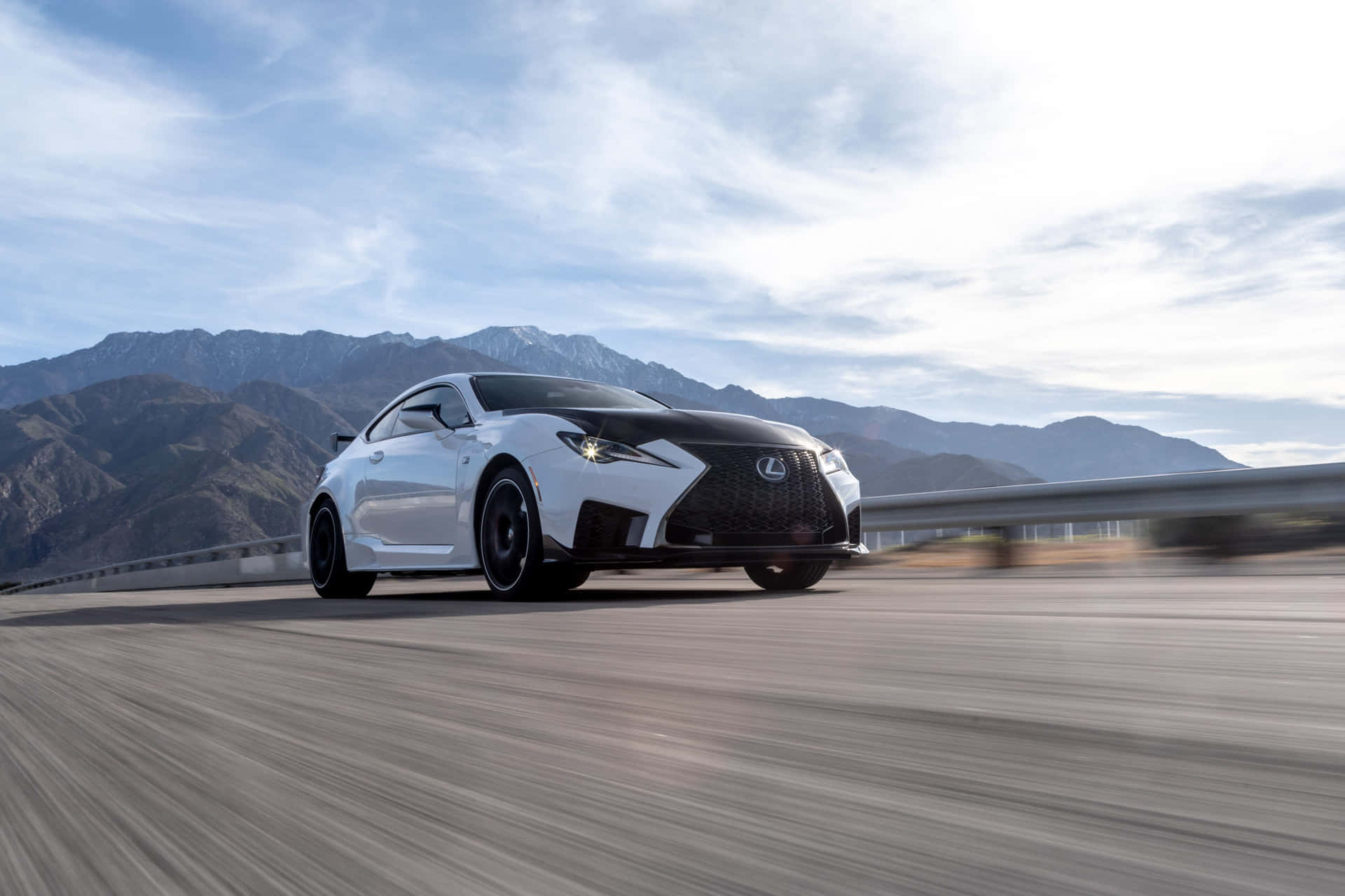 Lexus Rc F 桌布 壁紙 — 一輛白色Lexus跑車在部分多雲的天空下，沿著雪山峰頂的山區高速公路飛馳。