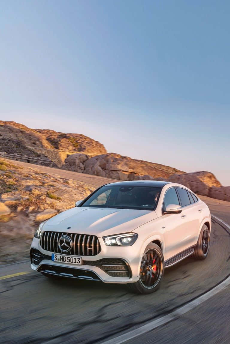 Family Car 桌布 壁紙 — 一輛白色Mercedes-AMG GLE63 S Coupe在日落時分沿著蜿蜒的山路疾馳，背景是岩石地形。