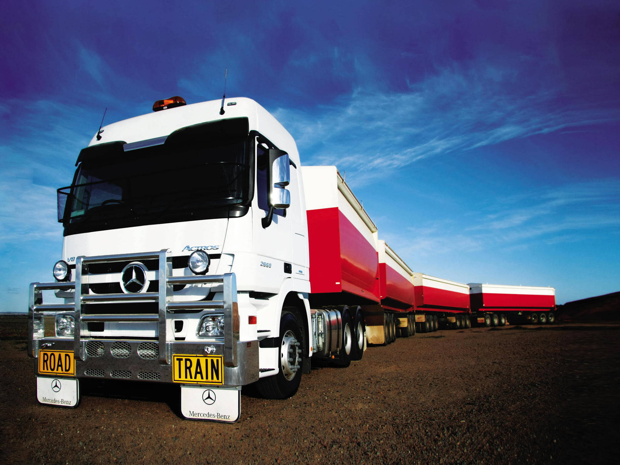Trucks 桌布 壁紙 — 一輛白色Mercedes-Benz Actros貨車搭配紅色拖車，停在泥土路上，天空湛藍，白雲輕飄。