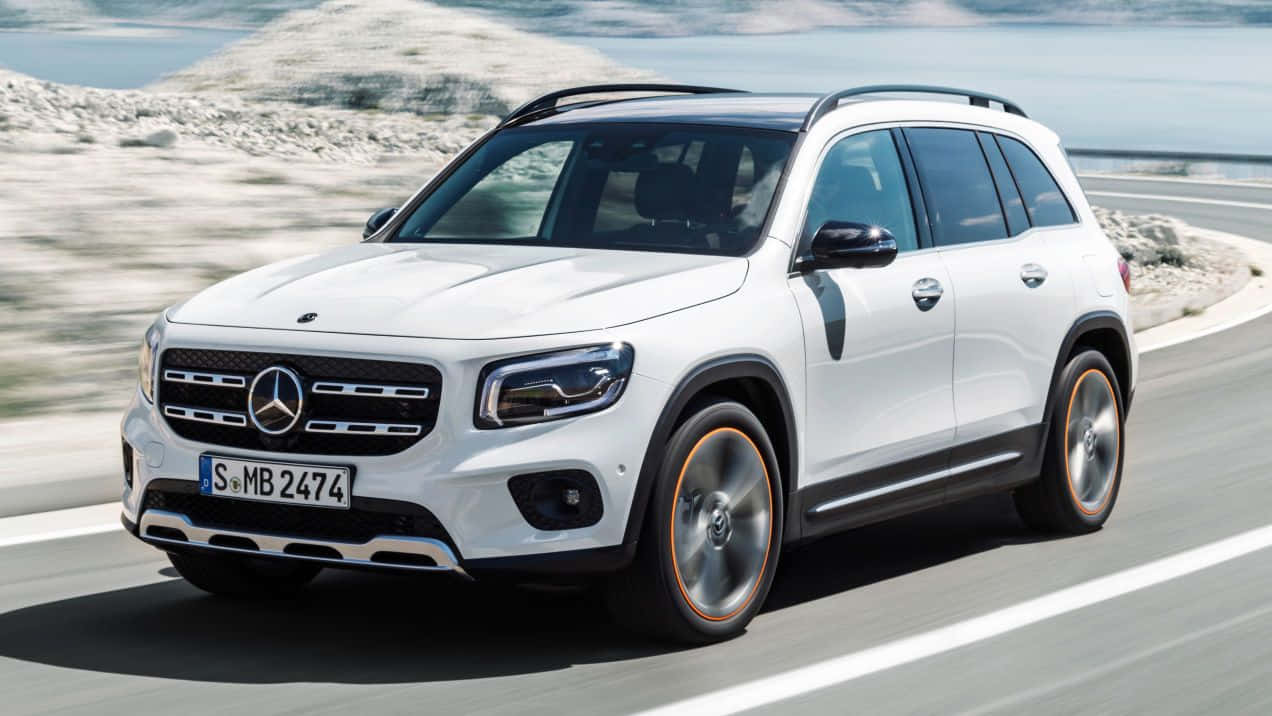 Family Car 桌布 壁紙 — 一輛白色Mercedes-Benz GLB SUV沿著海岸公路疾馳，背景有岩石懸崖和模糊的動態效果。