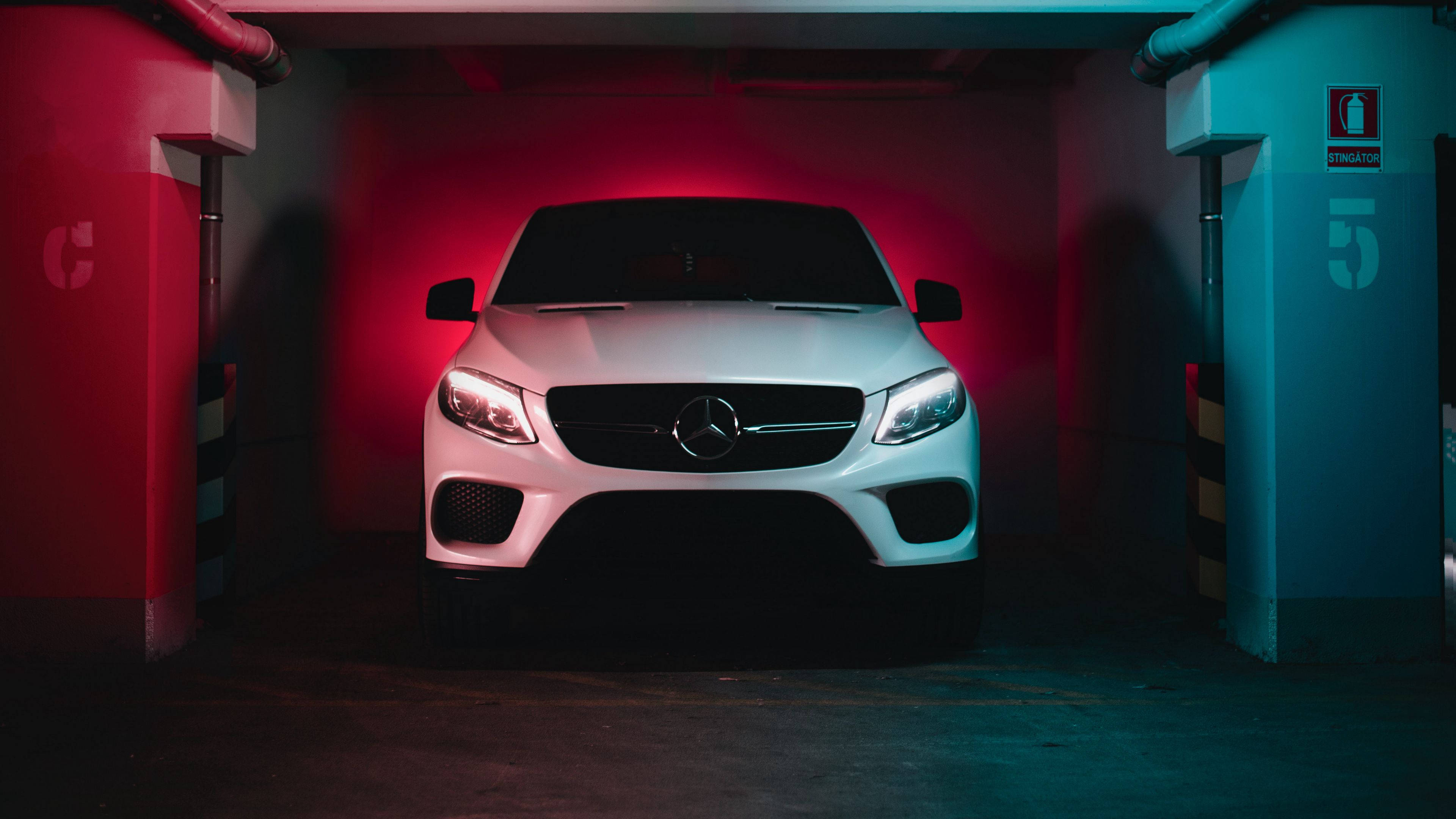 Mercedes 桌布 壁紙 — 一輛白色Mercedes SUV在昏暗的地下停車場中，在戲劇性的紅色和藍色霓虹燈下閃耀。