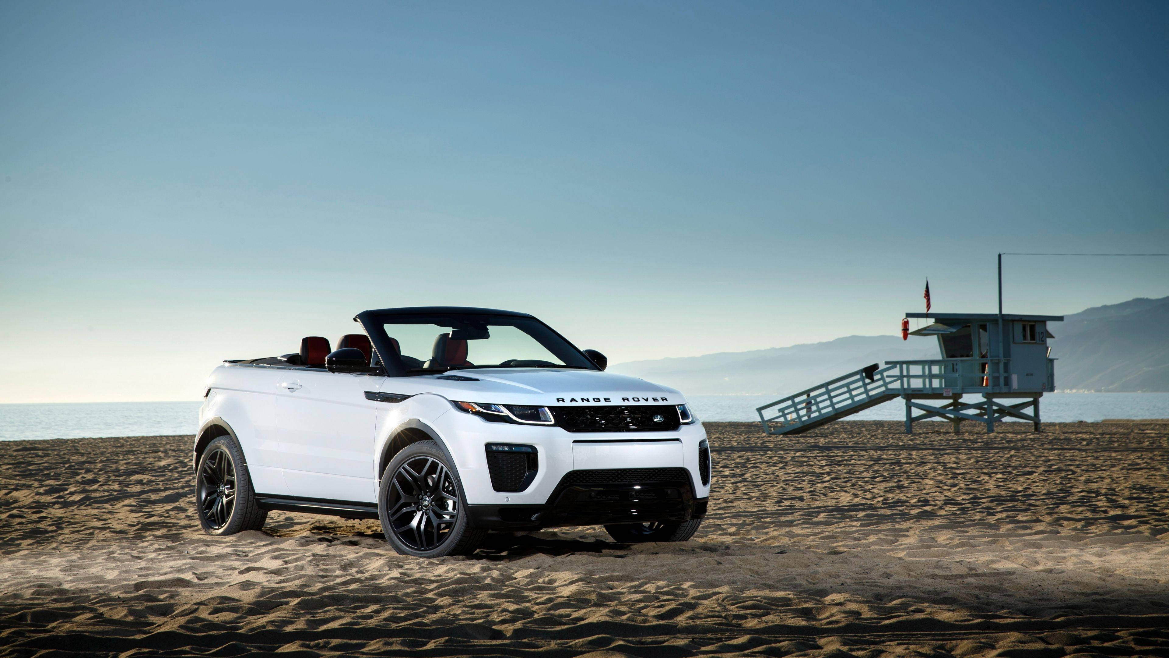 高清 桌布 壁紙 — 一輛白色Range Rover Evoque Convertible停放在沙灘上，旁邊是救生員瞭望塔，天空清澈湛藍。
