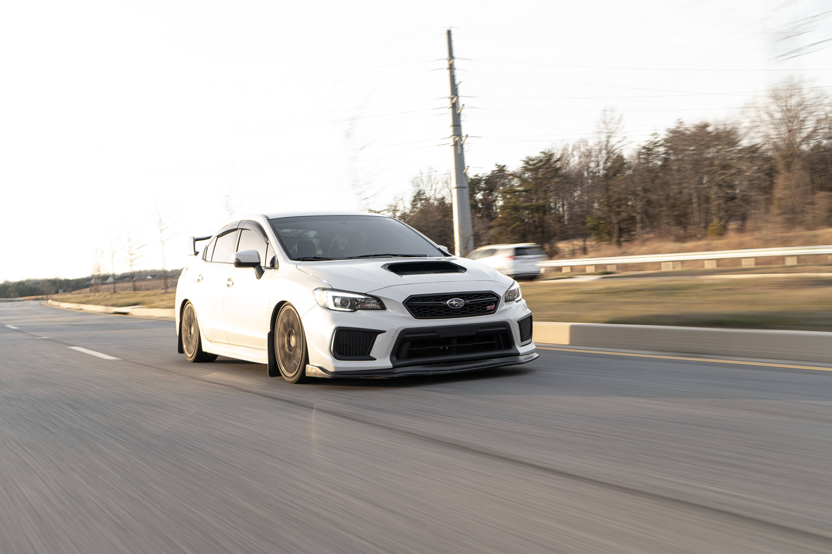 昴 桌布 壁紙 — 一輛白色Subaru WRX STI在鄉村高速公路上高速行駛，動態模糊傳達出高速度和力量。