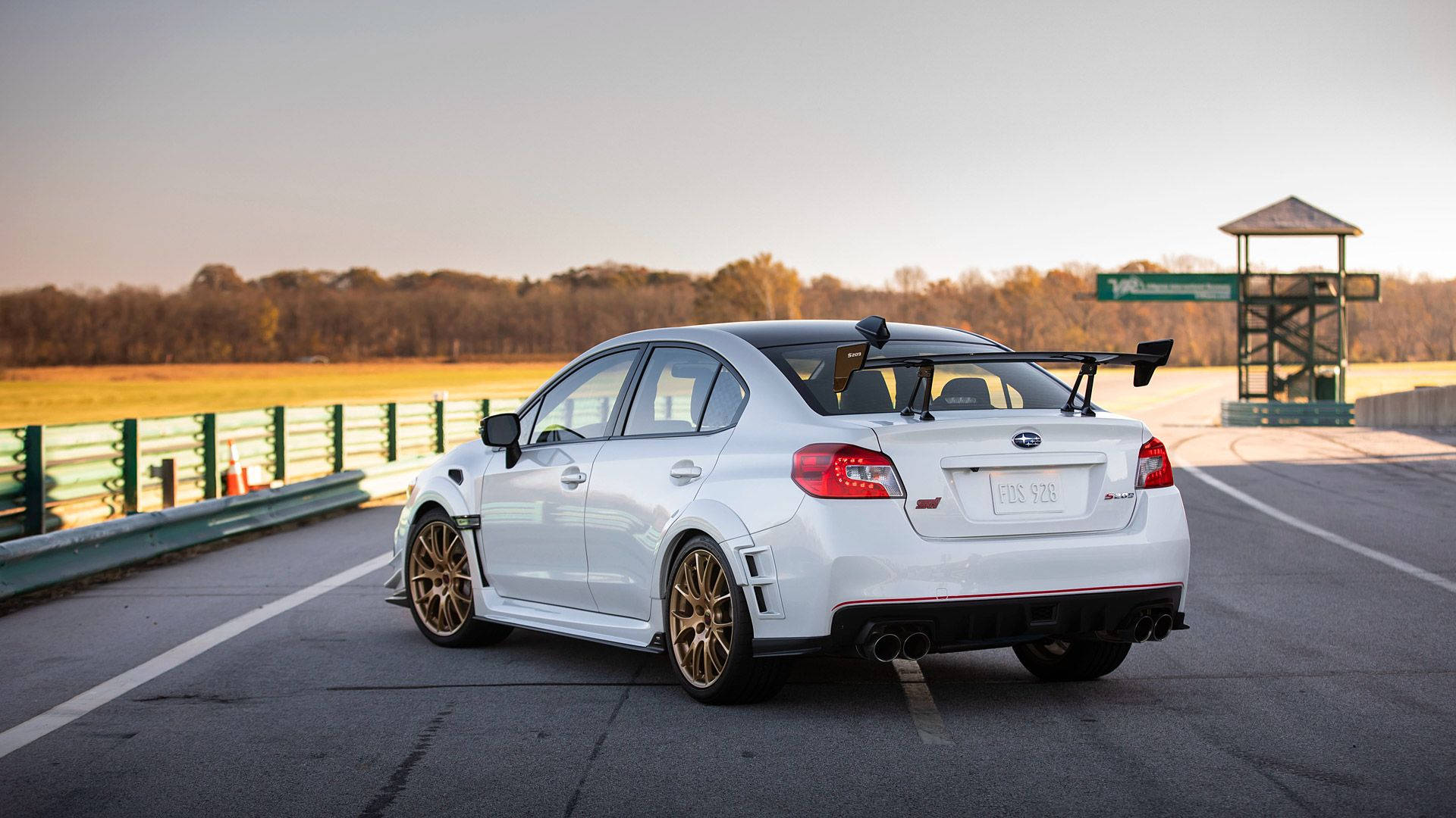 Subaru 桌布 壁紙 — 一輛白色Subaru WRX STI配備金色輪圈及大型尾翼，在黃金時段的賽道上蓄勢待發。