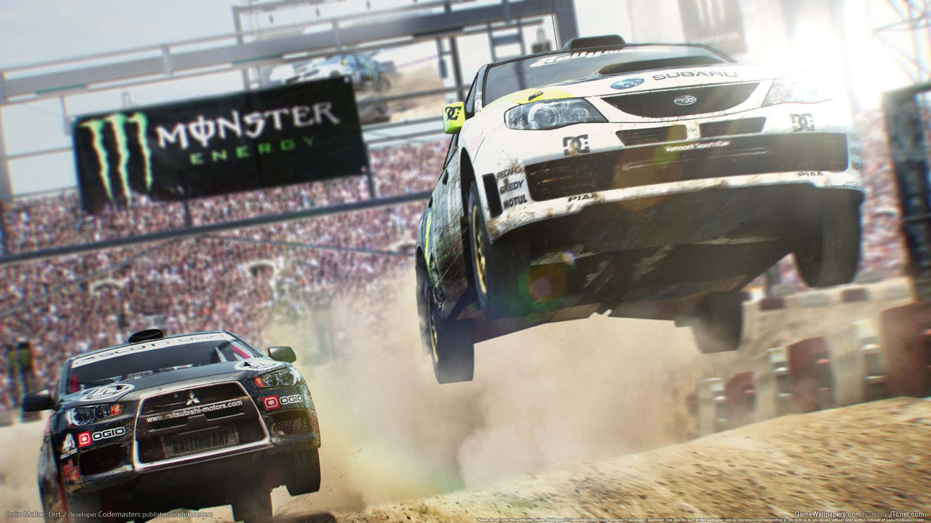 1080p Dirt 3 桌布 壁紙 — 一輛白色Subaru拉力賽車飛越泥地跳台，而一輛黑色Mitsubishi在咆哮的人群前於下方飛馳。