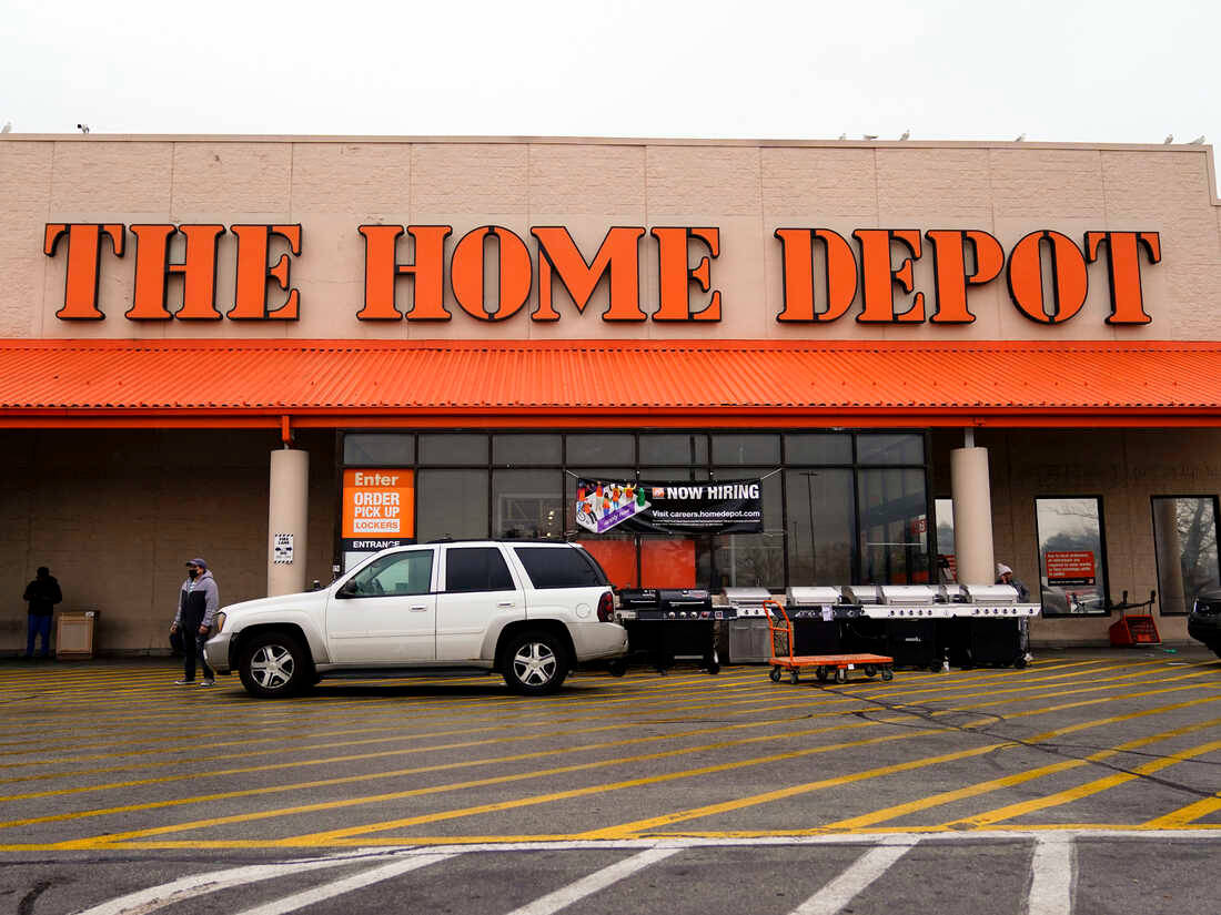 Home Depot 桌布 壁紙 — 一輛白色SUV停在一間Home Depot商店前，商店有橙色標誌和黃色停車線，天空多雲。