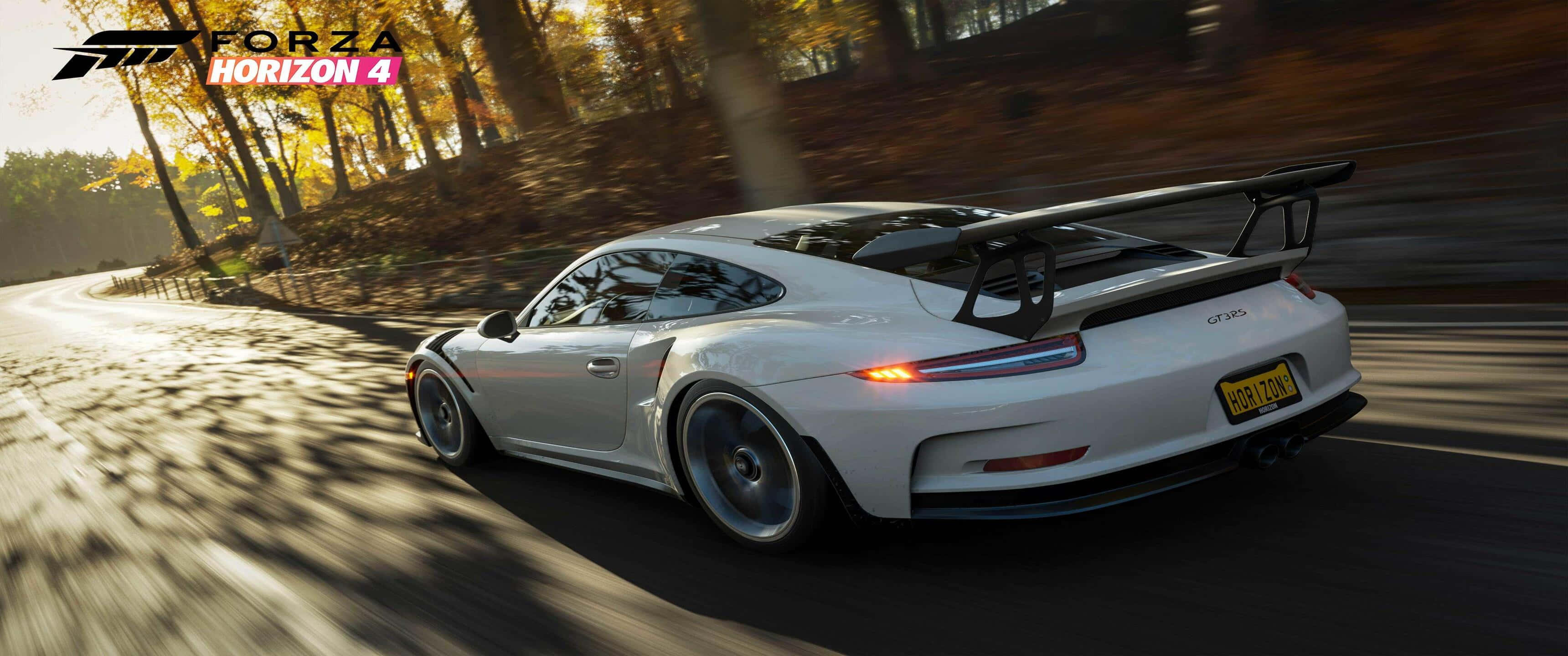3440x1440p Forza Horizon 4 桌布 壁紙 — 一輛白色保時捷911 GT3 RS在陽光明媚的秋日森林中疾馳，道路上呈現動態模糊效果。