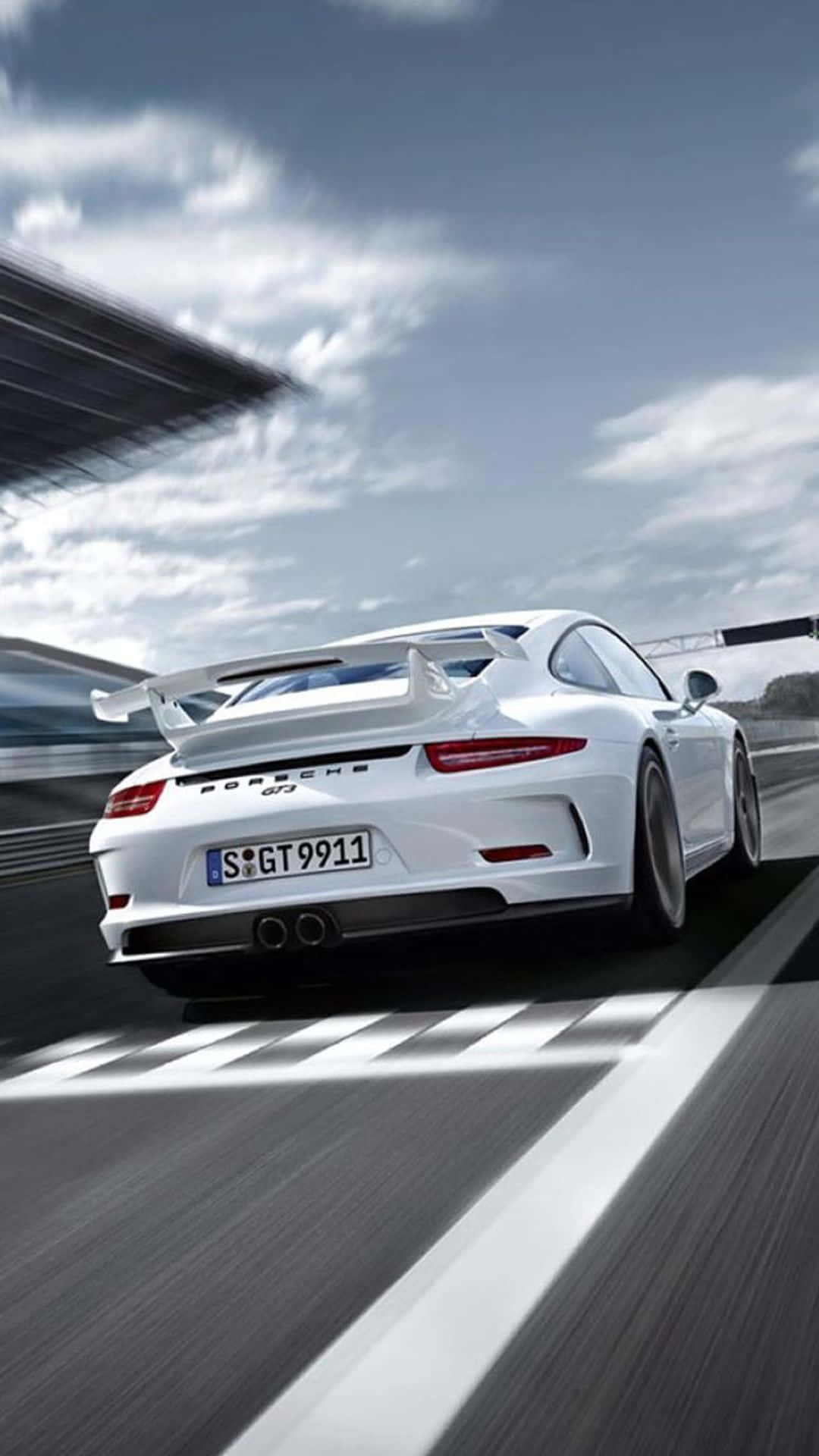 汽車 桌布 壁紙 — 一輛白色保時捷911 GT3在多雲的天空下，以動態模糊效果在賽道上奔馳。
