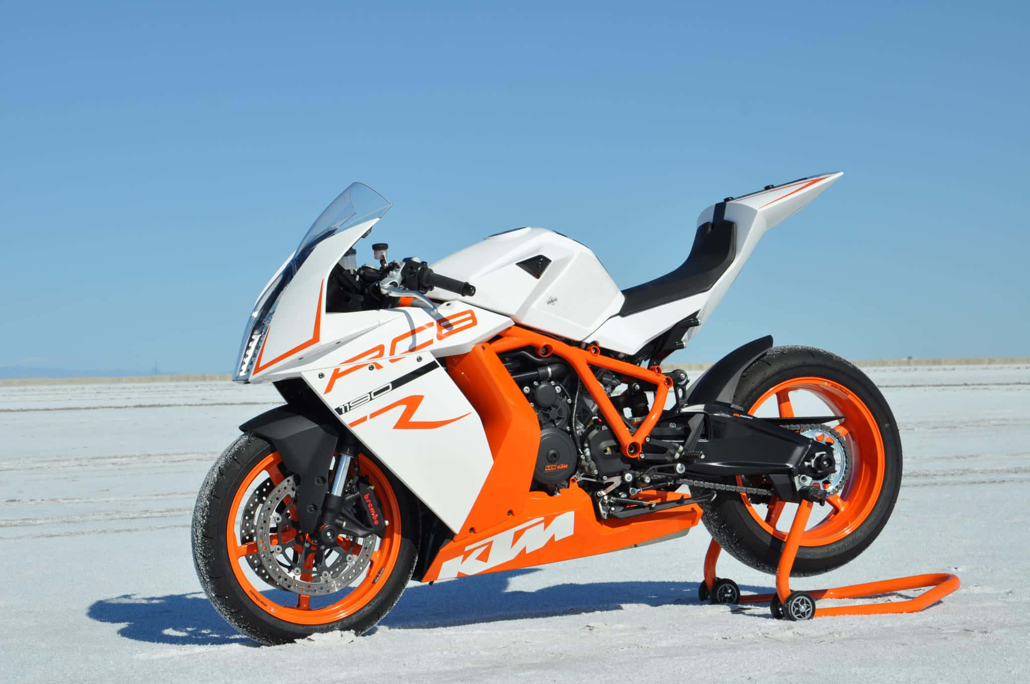 機車 桌布 壁紙 — 一輛白色和橙色的KTM RC8運動摩托車站在鹽灘上，天空清澈湛藍。
