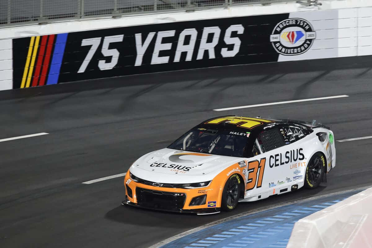 nascar 桌布 壁紙 — 一輛白色和橙色的NASCAR賽車，編號31，在明亮的體育場燈光下於夜間賽道上飛馳。