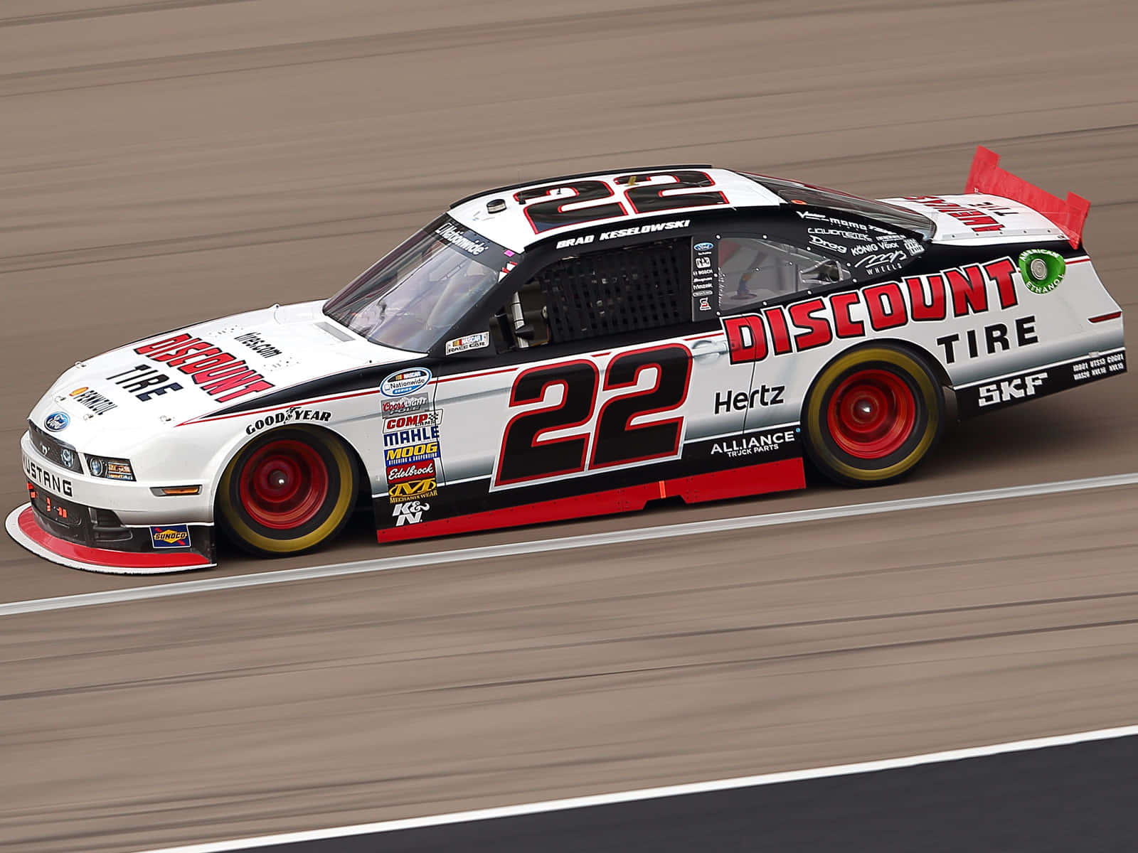 nascar 桌布 壁紙 — 一輛白色和紅色的#22 NASCAR賽車在模糊的賽道上疾馳，贊助商標誌清晰可見。