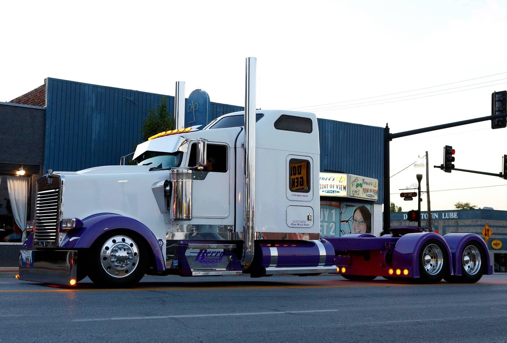 Kenworth 桌布 壁紙 — 一輛白色和紫色的半掛卡車帶有鍍鉻裝飾，在黃昏時分停在一個小鎮的交通燈前。