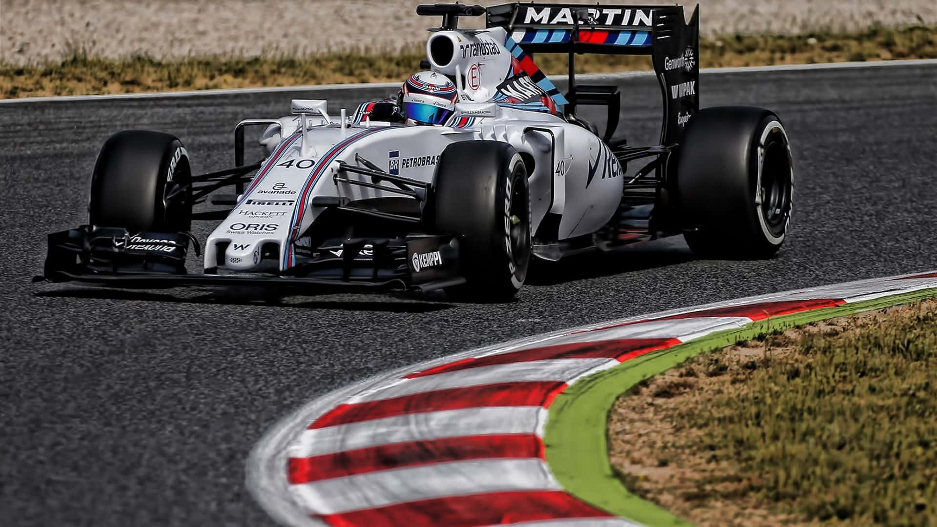 F1 2016 桌布 壁紙 — 一輛白色和藍色的 Formula 1 賽車，號碼 40，在陽光明媚的賽道上緊貼著紅白綠三色路緣石的彎道飛馳。