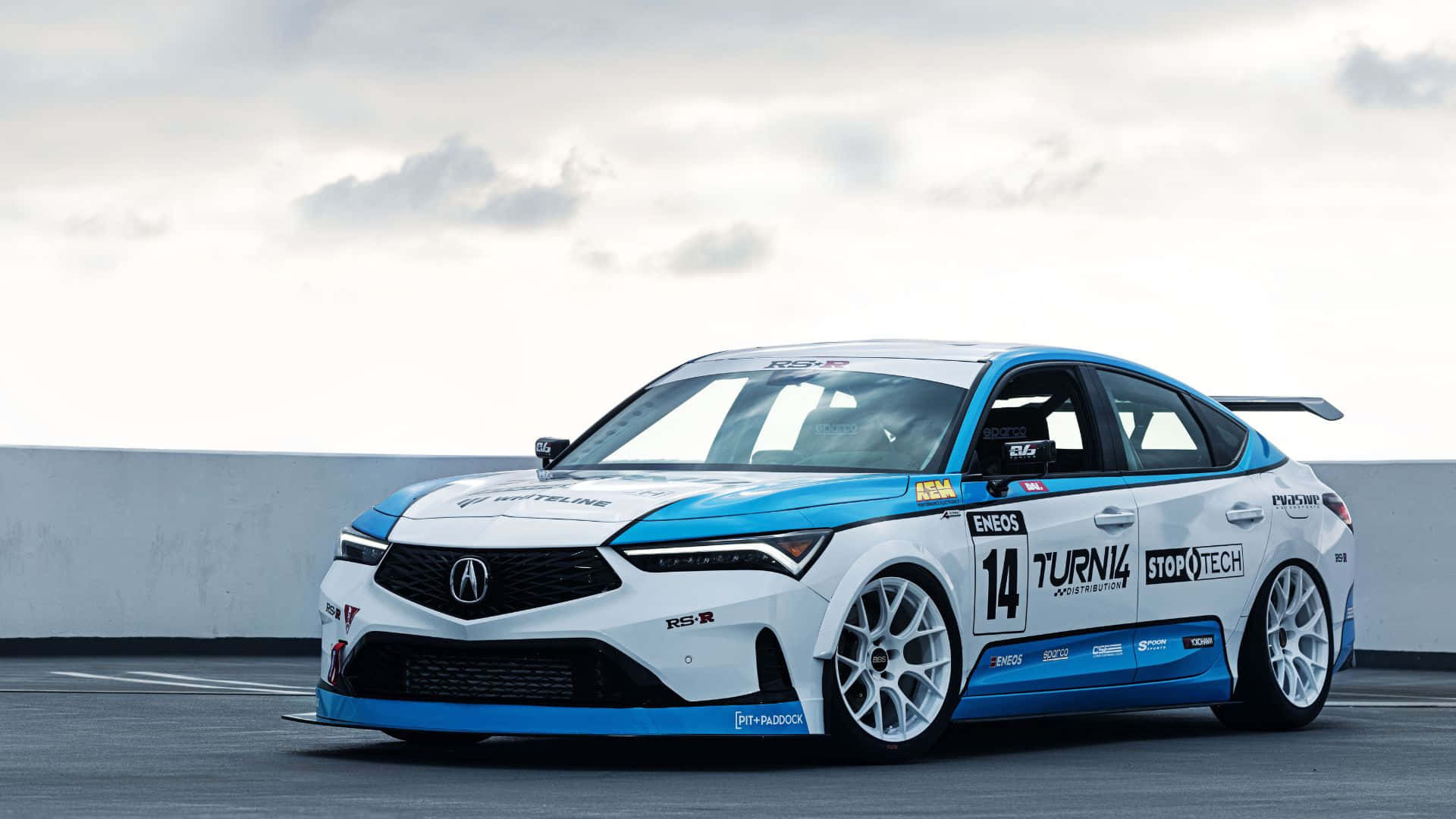 Acura Integra 桌布 壁紙 — 一輛白色和藍色的14號賽車停泊在陰天下的賽道上。