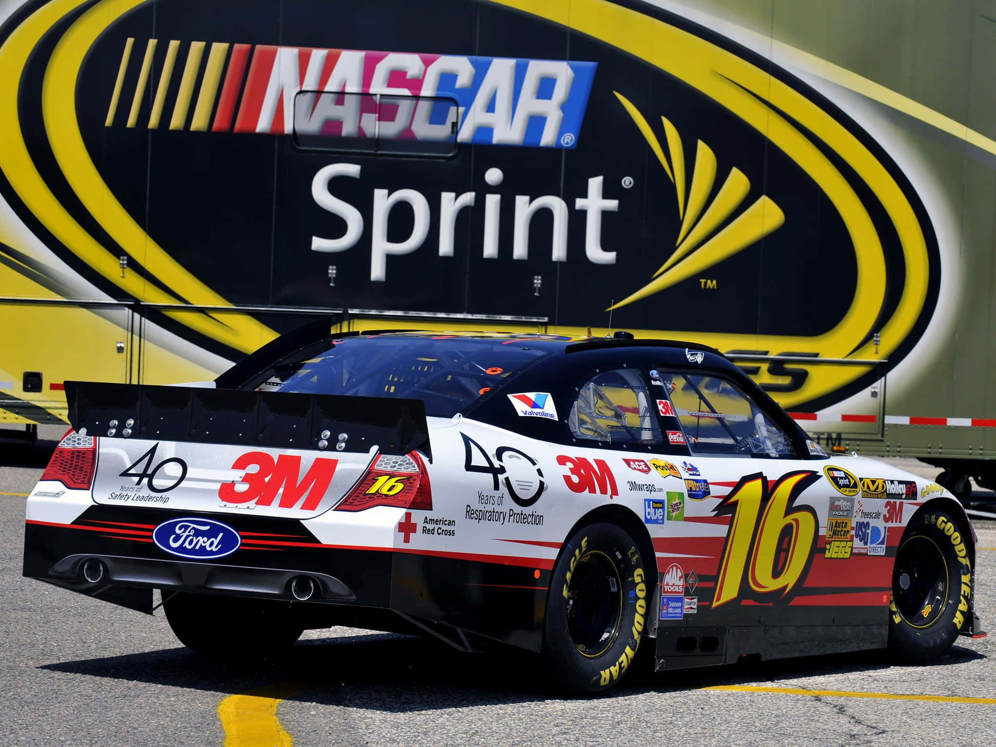 nascar 桌布 壁紙 — 一輛白色和黑色的NASCAR賽車，帶有16號和3M贊助，停在一輛大型Sprint卡車前面。