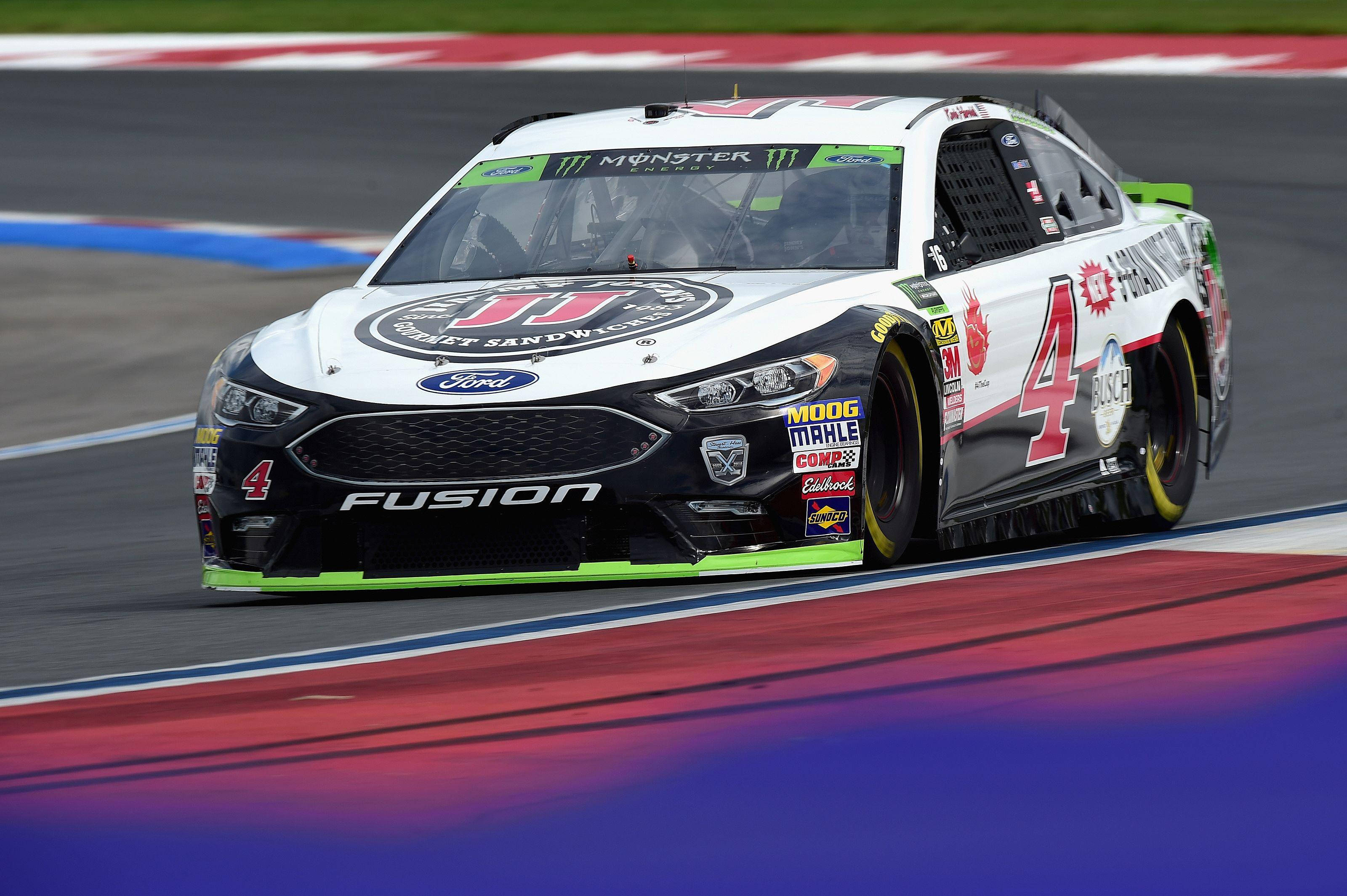 Kevin Harvick 桌布 壁紙 — 一輛白色和黑色的福特Fusion賽車，號碼4，沿著帶有紅色、藍色和白色路緣的賽道飛馳。
