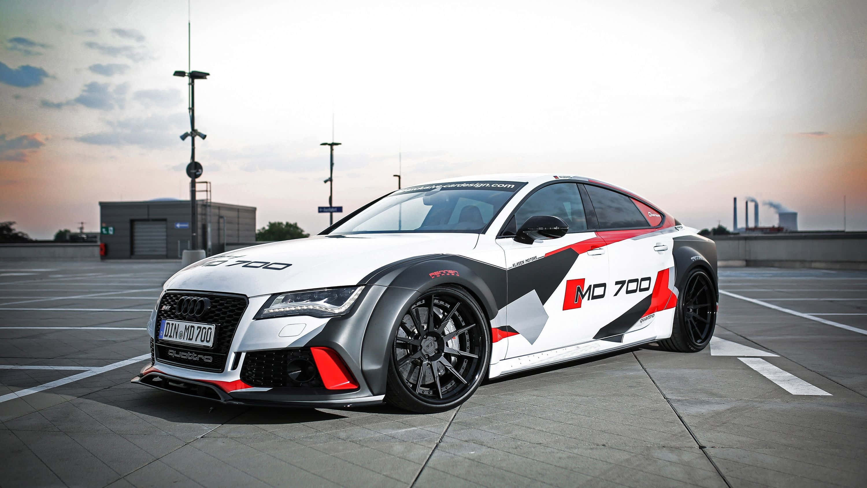 Car Design 桌布 壁紙 — 一輛白色奧迪RS7，帶有紅黑賽車塗裝，停在日落時分的混凝土場地上。