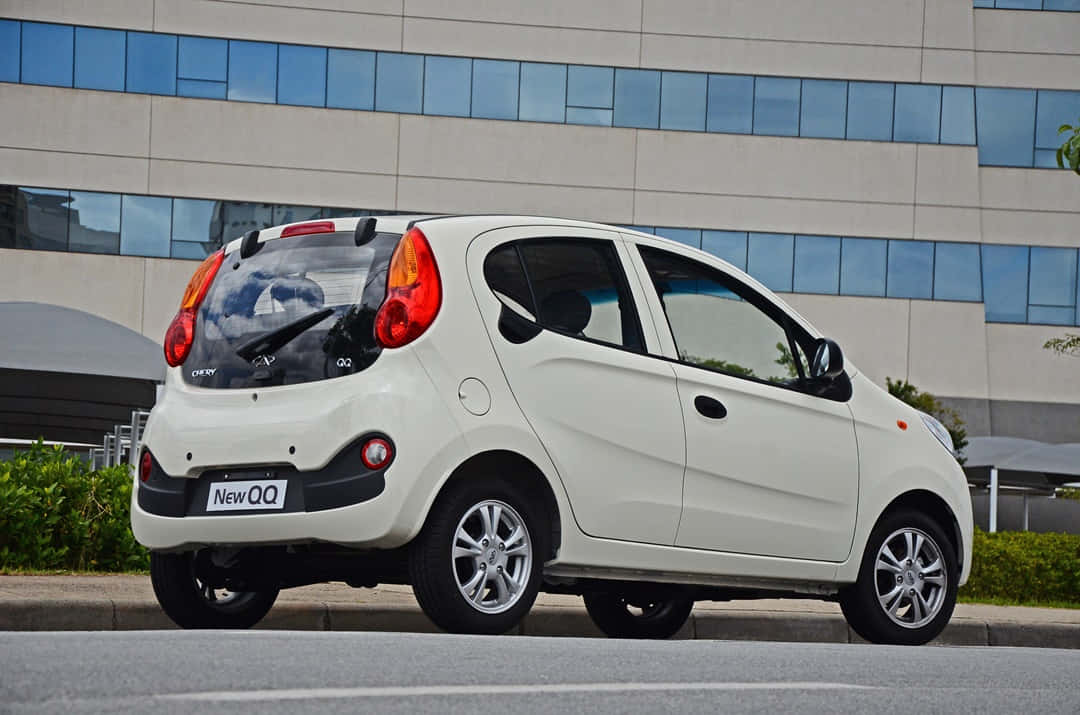 Chery 桌布 壁紙 — 一輛白色小型汽車停放在城市街道上，背景是一座現代玻璃建築。