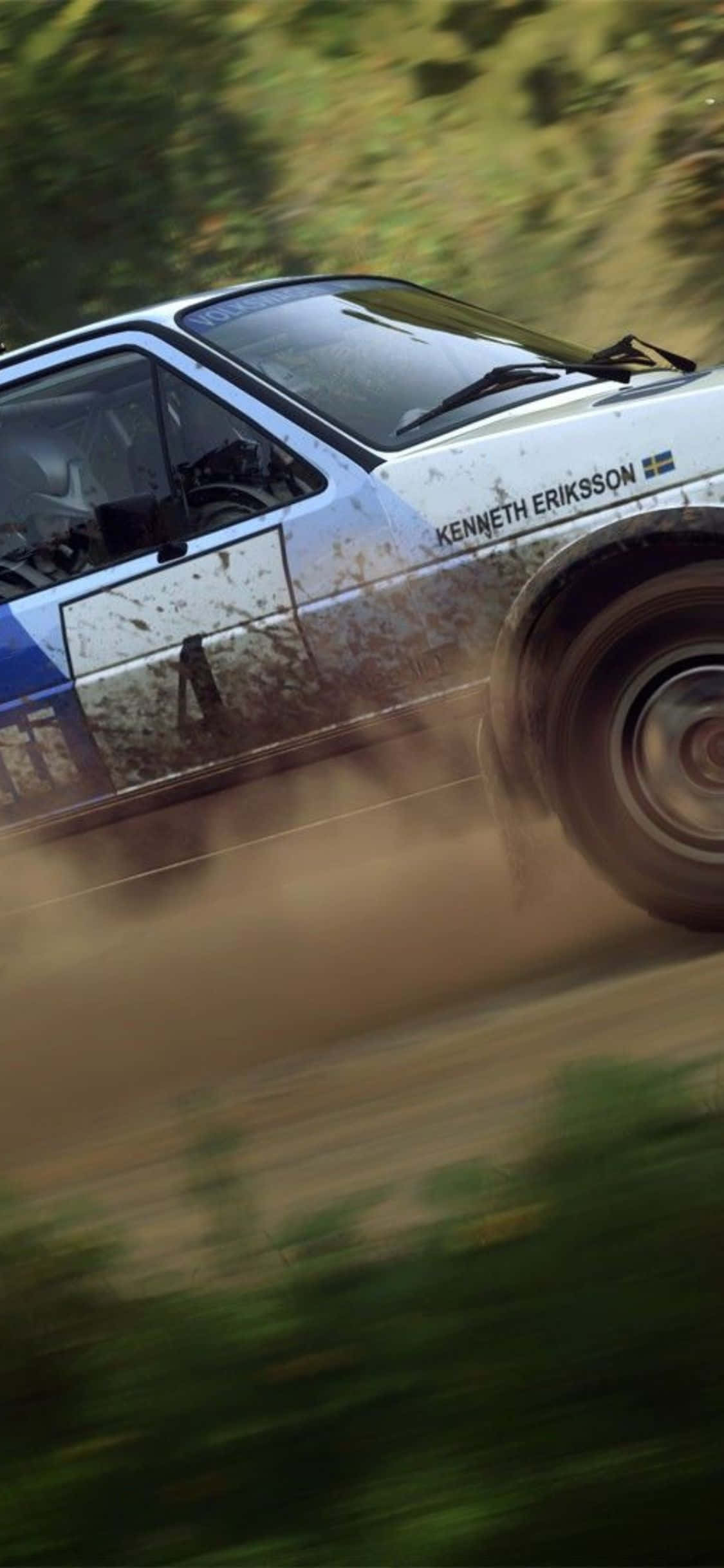 iPhone Xs Dirt Rally 桌布 壁紙 — 一輛白色拉力賽車濺滿泥濘，在森林中的泥路飛馳，揚起灰塵。