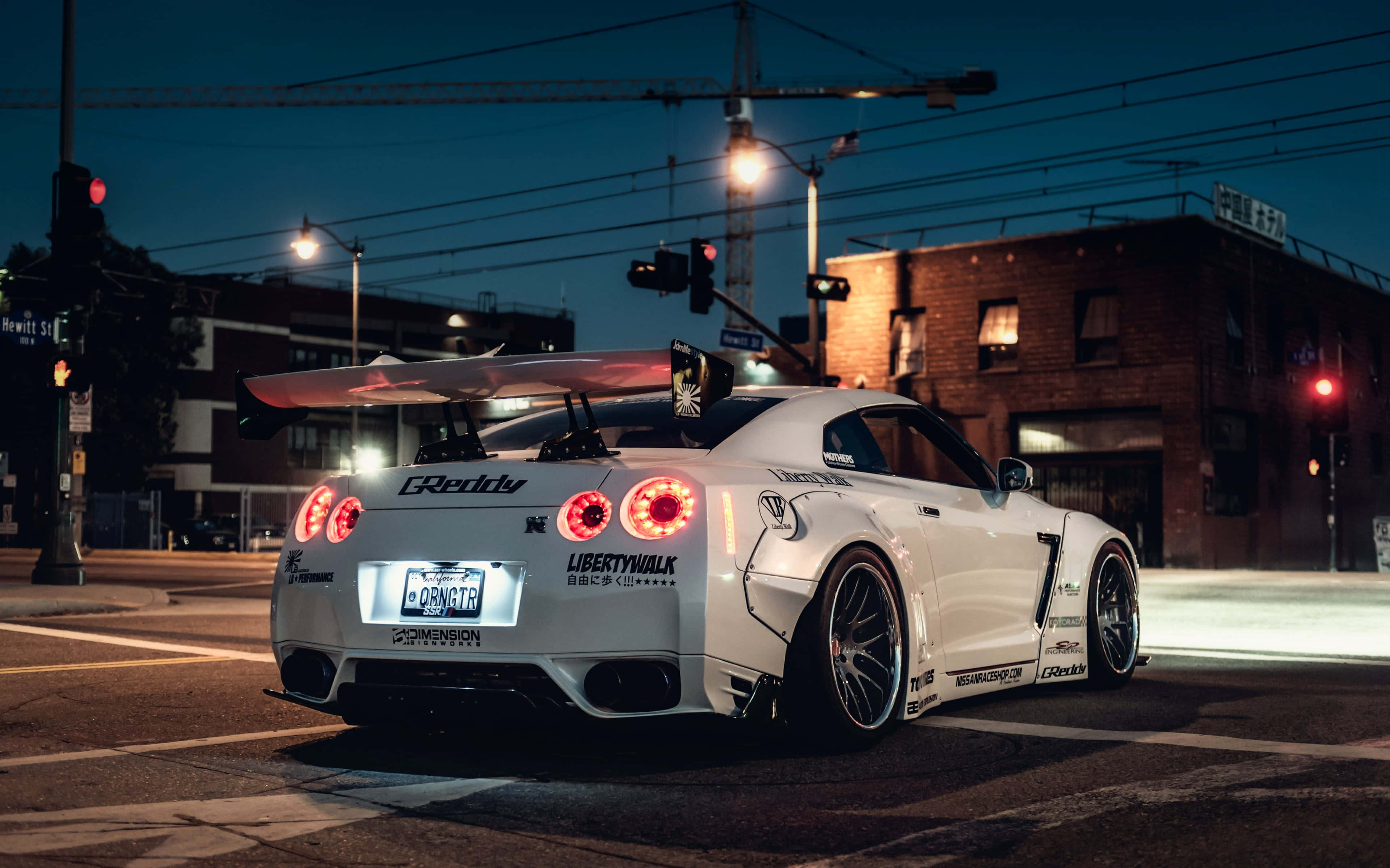 跑車 桌布 壁紙 — 一輛白色改裝日產GT-R，在暮色街燈下的城市十字路口停車，紅色尾燈閃爍。