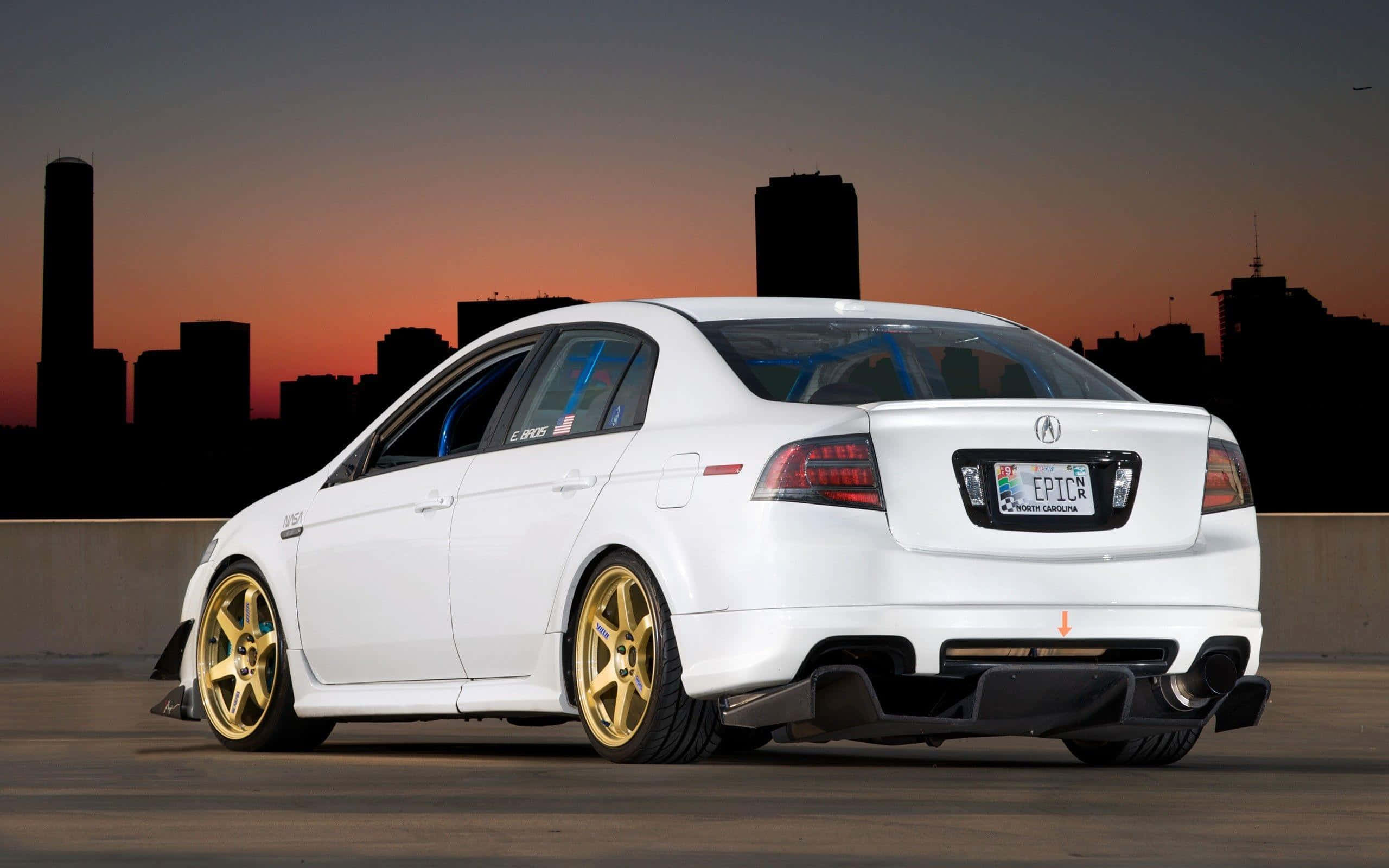 Acura Tl 桌布 壁紙 — 一輛白色改裝轎車搭配金色輪圈，停放在日落時分的城市高架橋上，背後是城市天際線剪影。